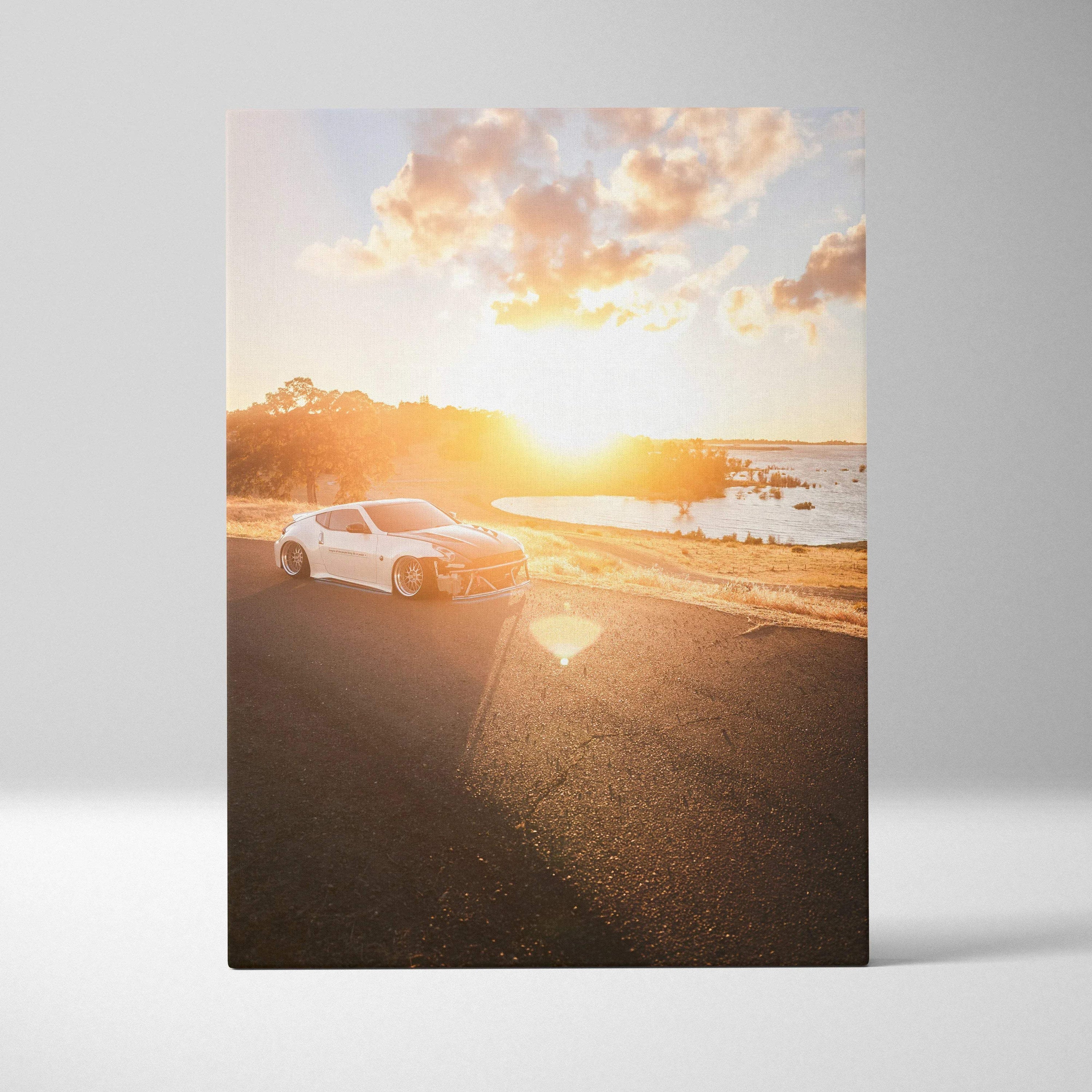 Vertical canvas art of a white Nissan 370z on a sunlit coastal road at sunset wall art.