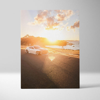 Vertical canvas art of a white Nissan 370z on a sunlit coastal road at sunset wall art.
