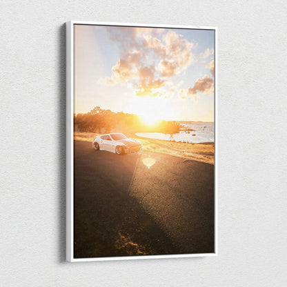 Vertical canvas art of a Nissan 370z parked by a sunlit coastal road at sunset.