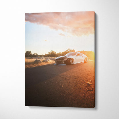 Nissan 370z driving on road at sunset canvas wall art with warm sky and golden light.
