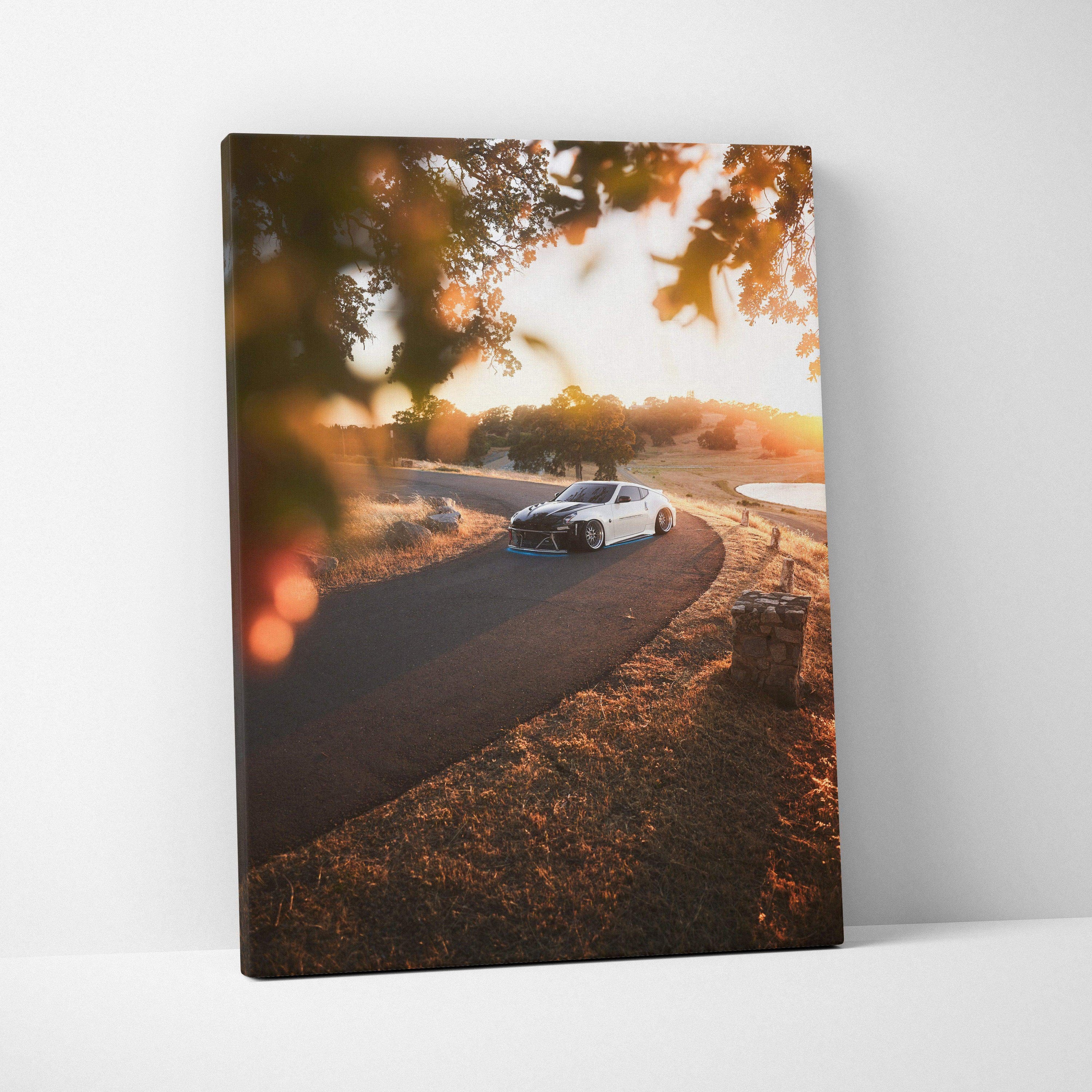 Nissan 370z driving on a winding road at sunset canvas wall art in warm tones.
