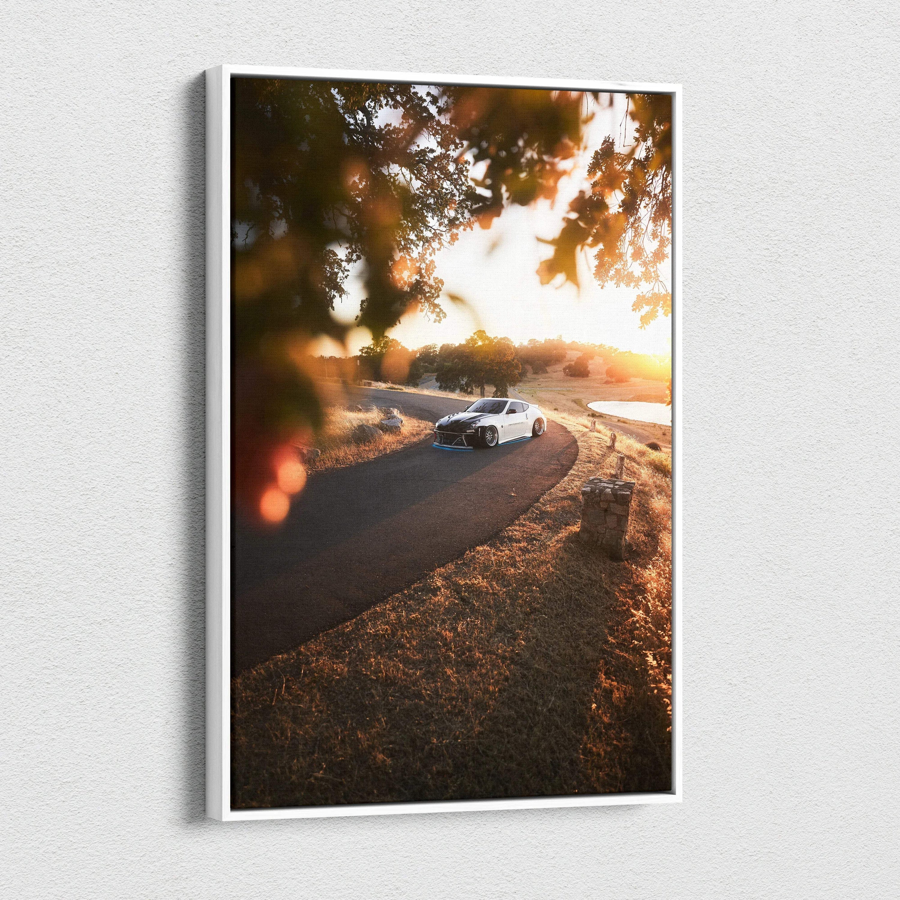 Vertical canvas wall art featuring a white Nissan 370z on a winding road at sunset with warm autumn tones.