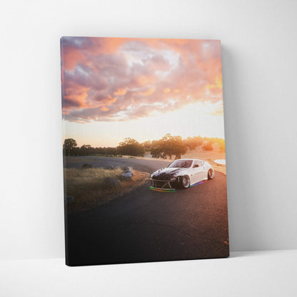 Vertical canvas wall art featuring a white Nissan 370z on a sunset racetrack with dramatic clouds.