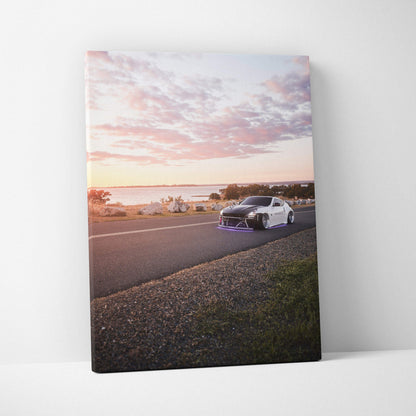 Nissan 370z driving on coastal road at sunset on vertical canvas wall art.