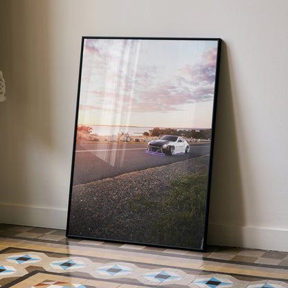 Framed Nissan 370z car poster with sunset sky, displayed as modern wall art on floor.