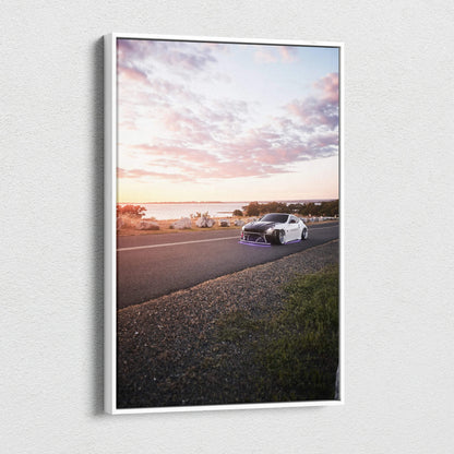 Nissan 370z driving on coastal road at sunset canvas wall art with vivid sky colors.