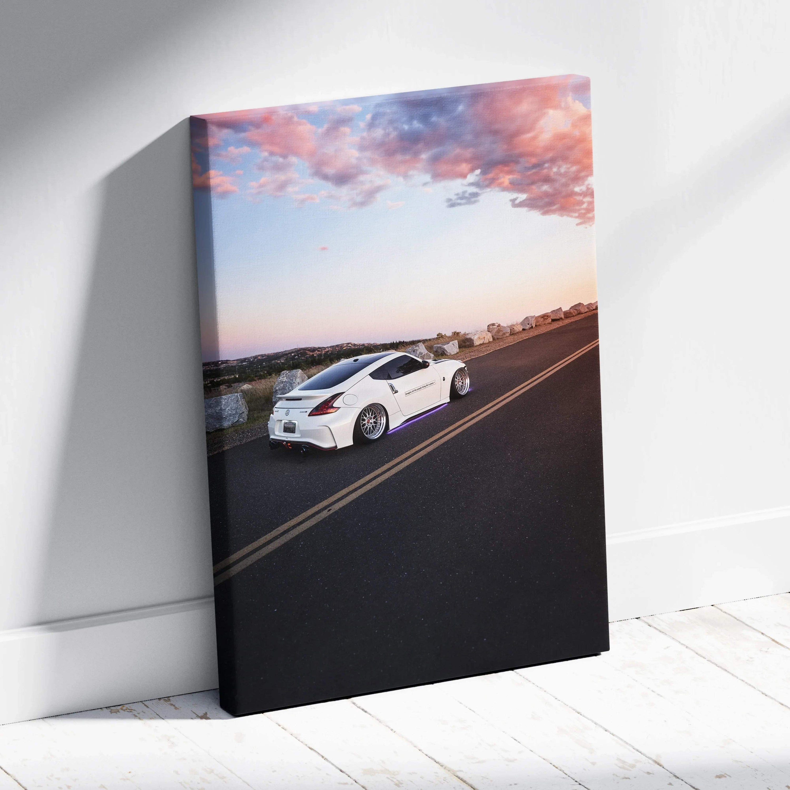 Vertical canvas wall art featuring a white Nissan 370z on a road at sunset.