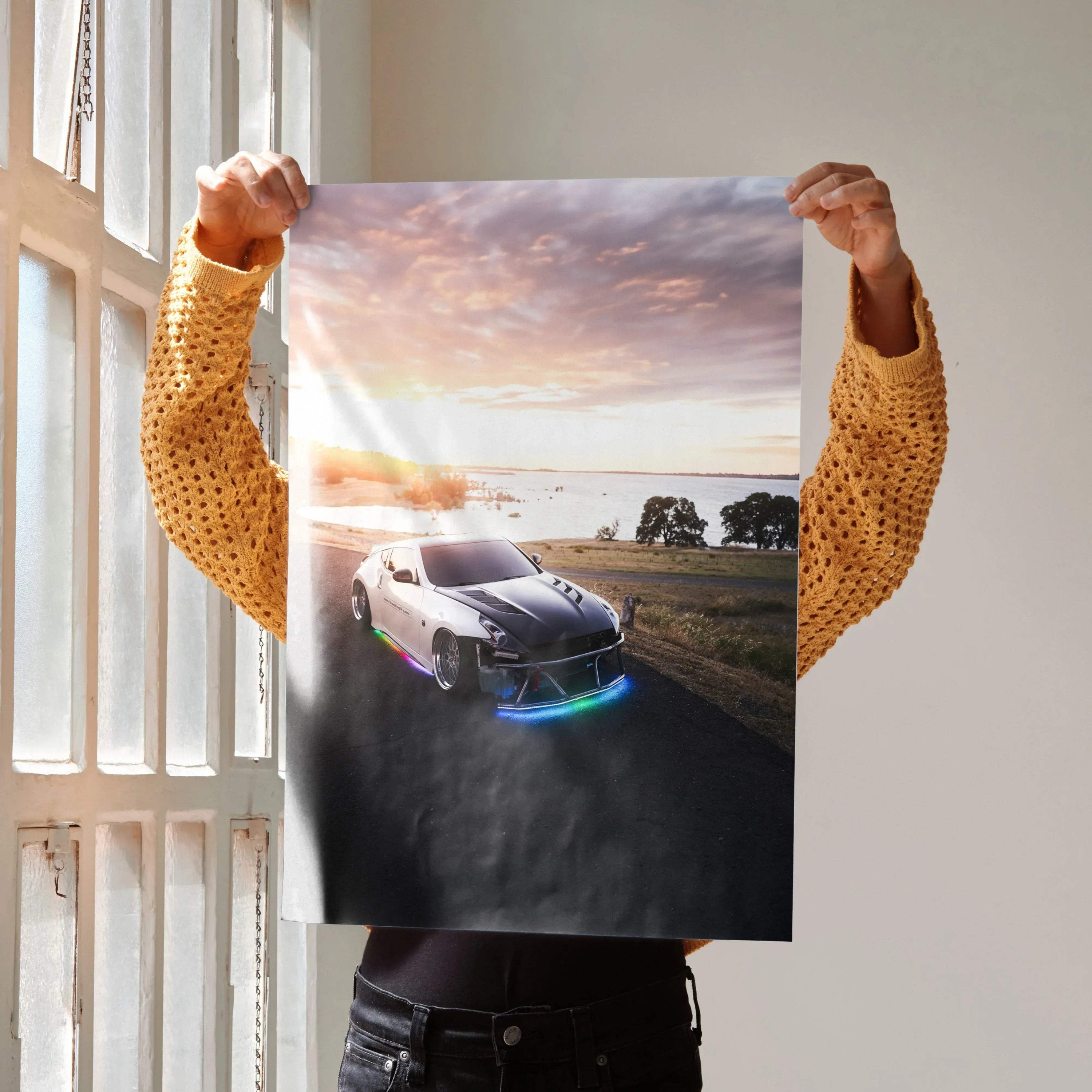 Nissan 370z poster wall art with glowing headlights at sunset on open road.