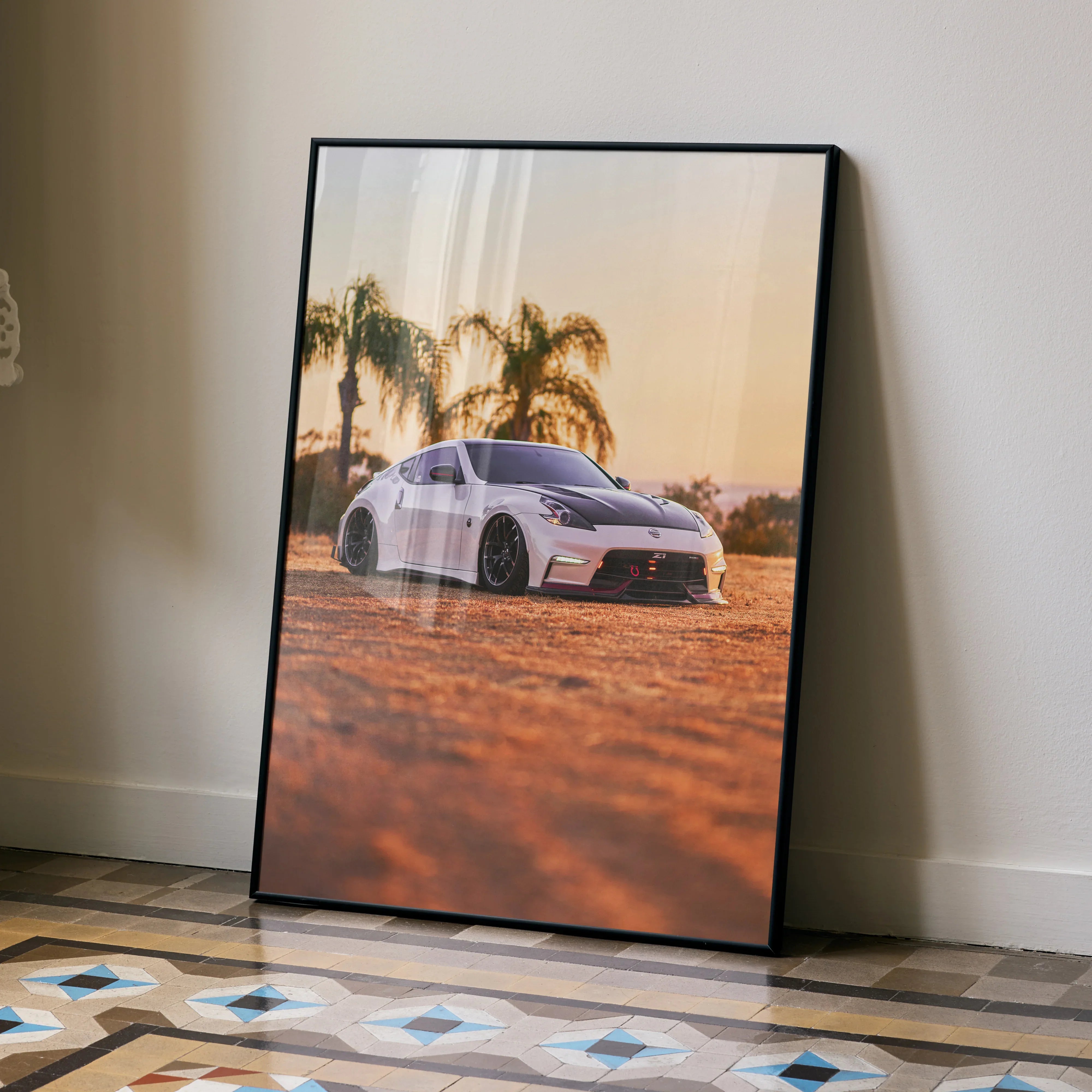 Nissan 370z poster wall art with sunset and palm trees in warm tones, framed and leaning on wall.