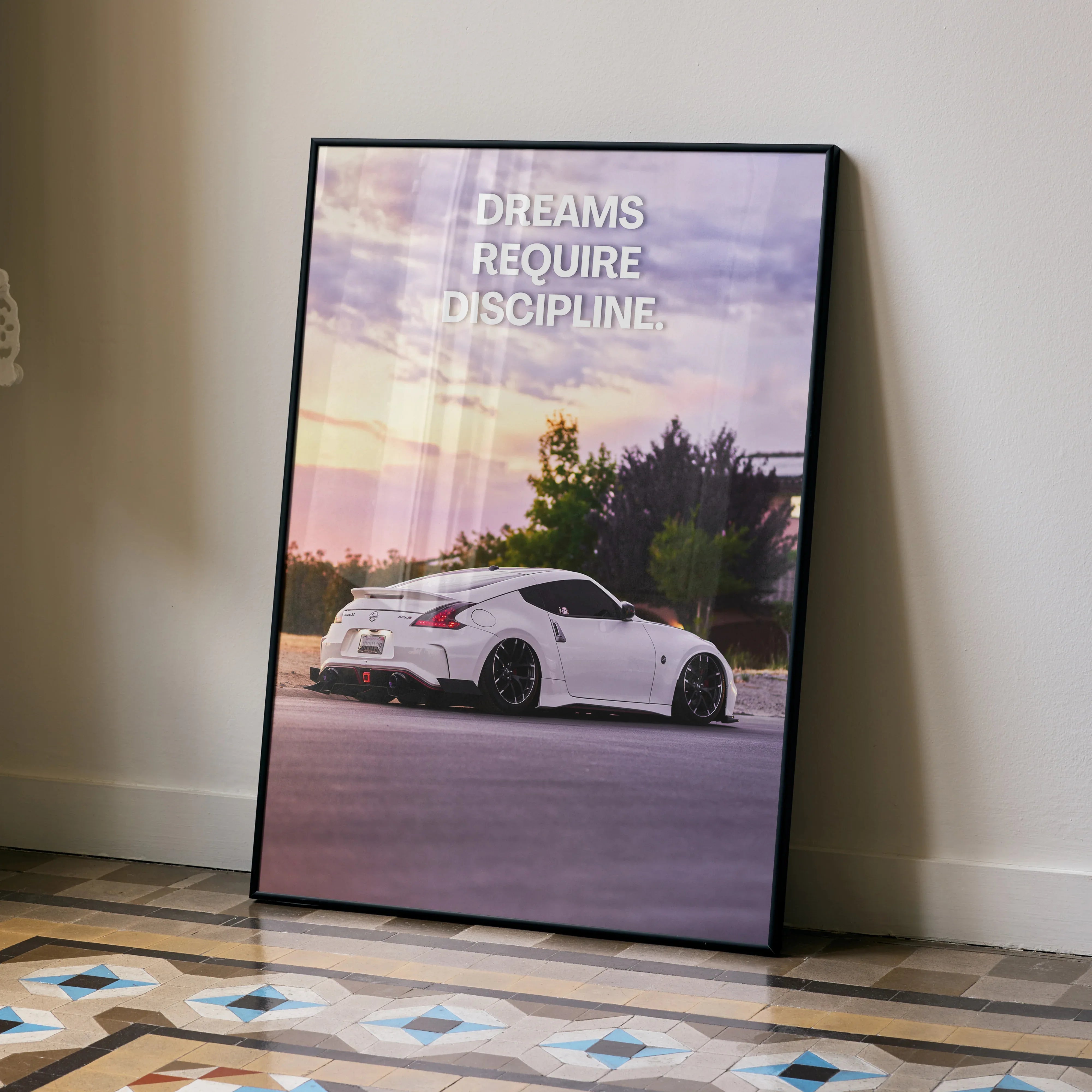 Motivational poster wall art featuring white Nissan 370z with "Dreams Require Discipline" text at sunset.