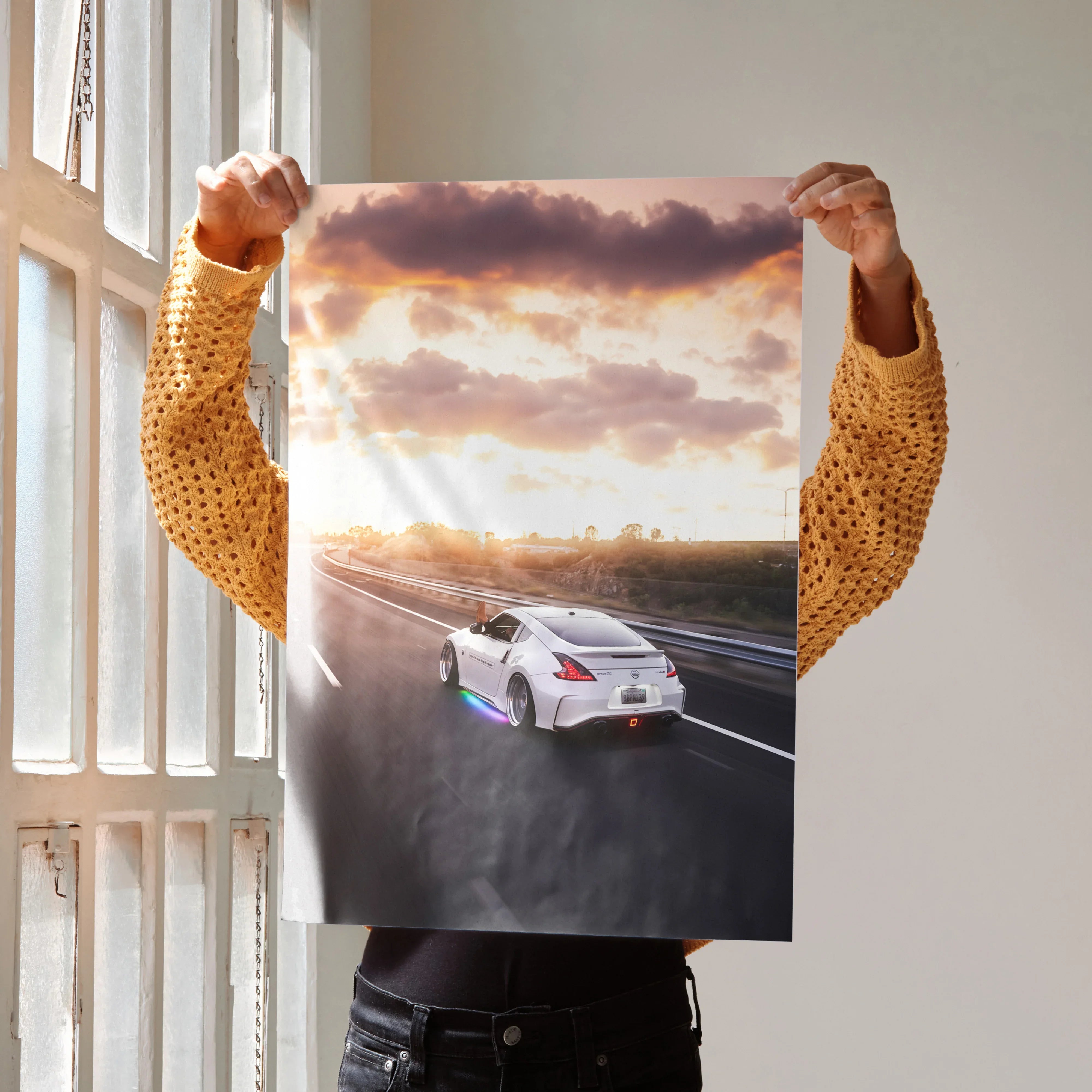 Nissan 370z driving on highway at sunset poster wall art with vibrant sky and road details.