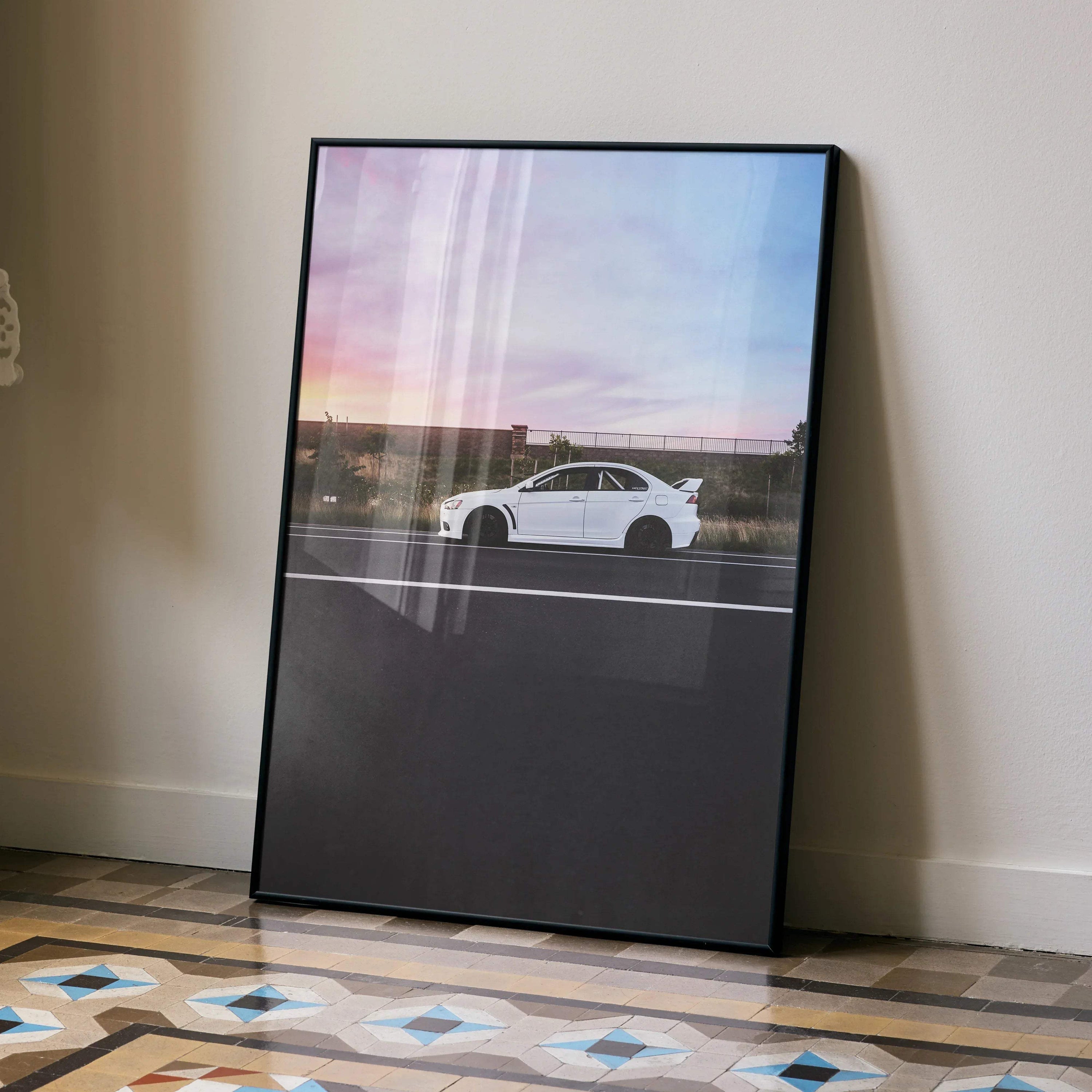 Mitsubishi Evo X poster wall art featuring white car against sunset sky in black frame.
