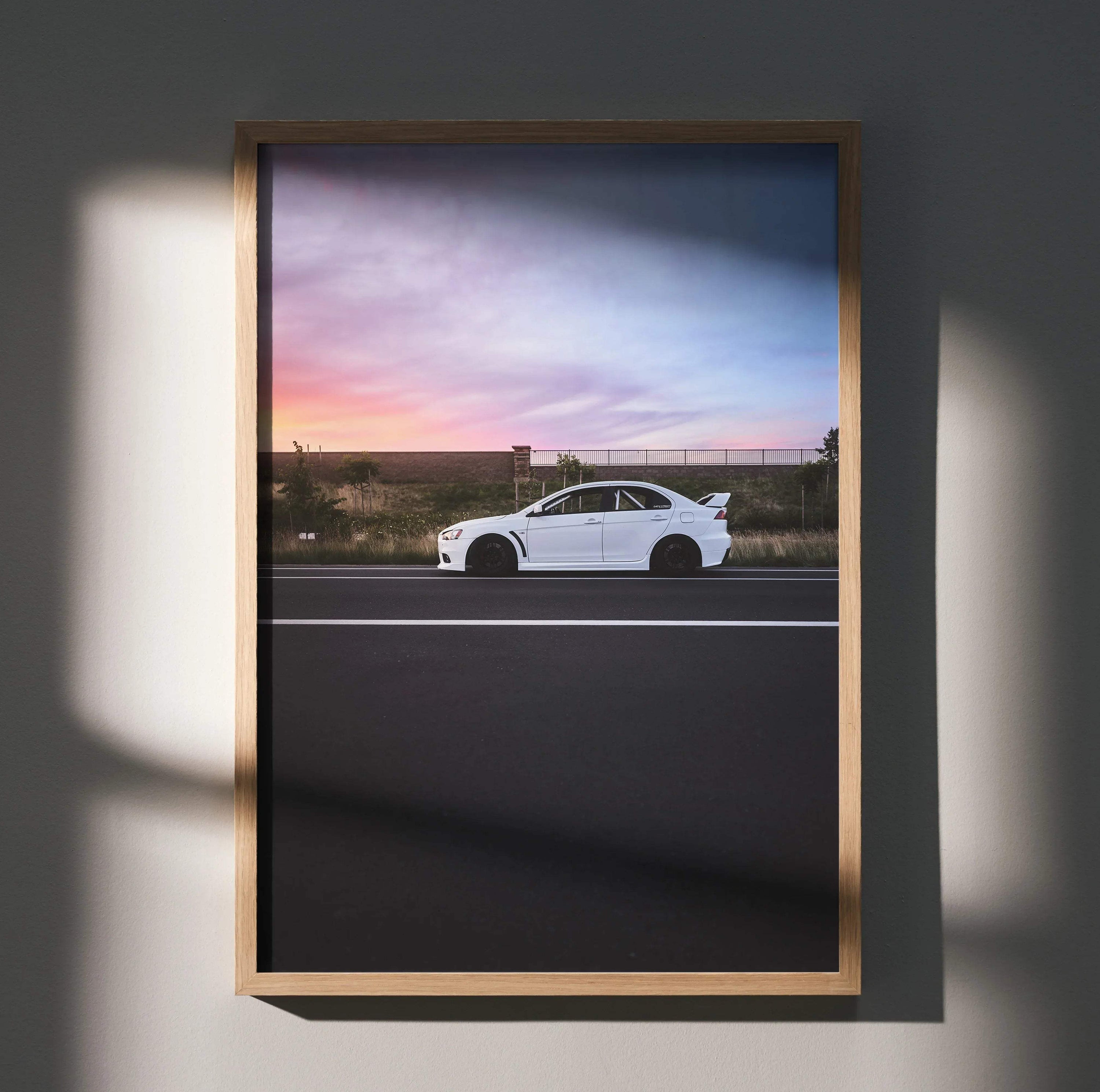 Mitsubishi Evo X poster with white car against vibrant sunset sky, framed wall art.