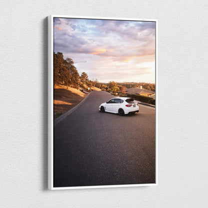 Vertical canvas art featuring a white Subaru WRX STI on a scenic road at sunset, wall art print.