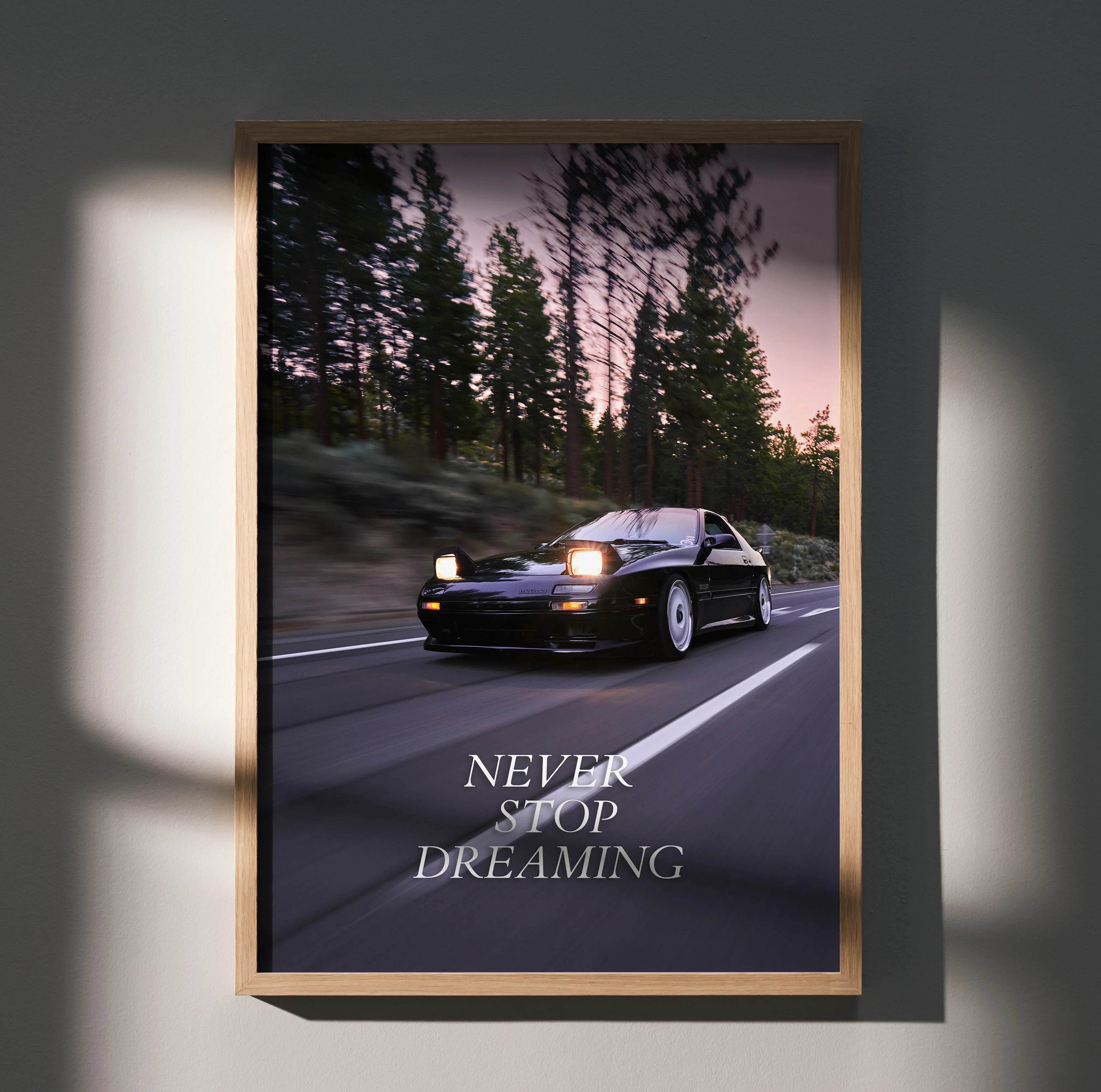Mazda FC RX7 driving at dusk on forest road motivational poster wall art with "Never Stop Dreaming" text.
