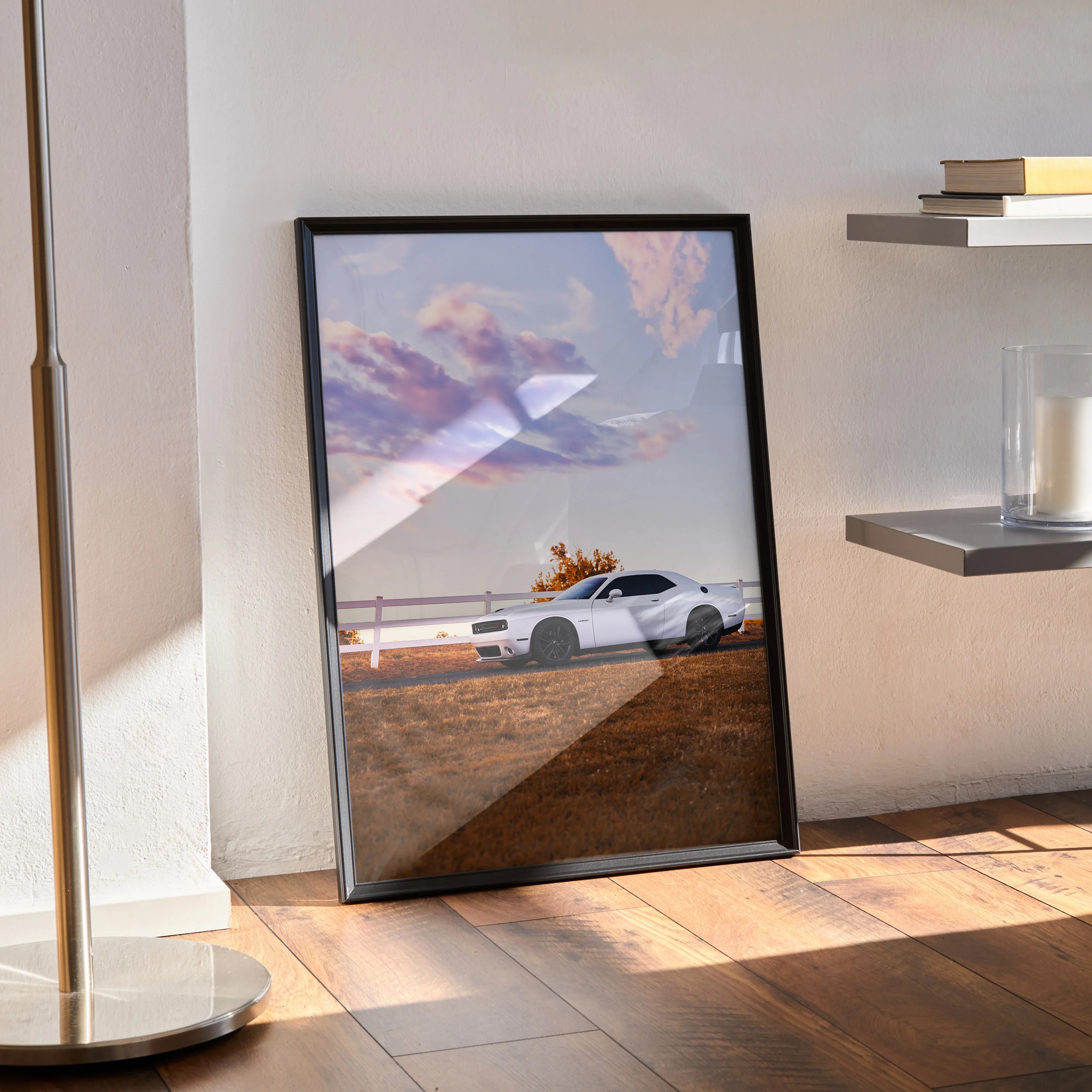 Dodge Challenger poster wall art featuring a white muscle car at sunset with dramatic clouds, framed and resting on wooden.