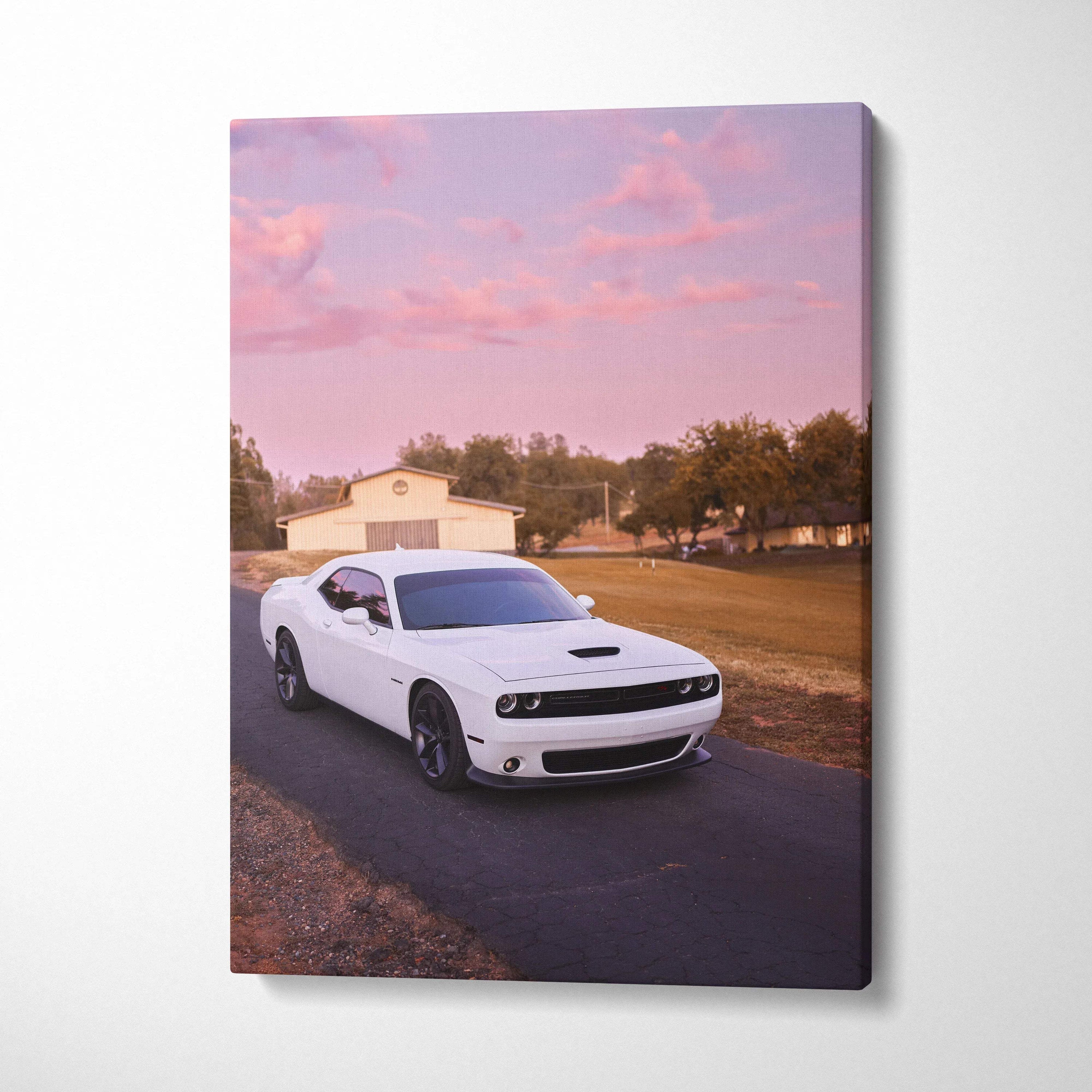 White Dodge Challenger on road at sunset with pink sky canvas wall art.