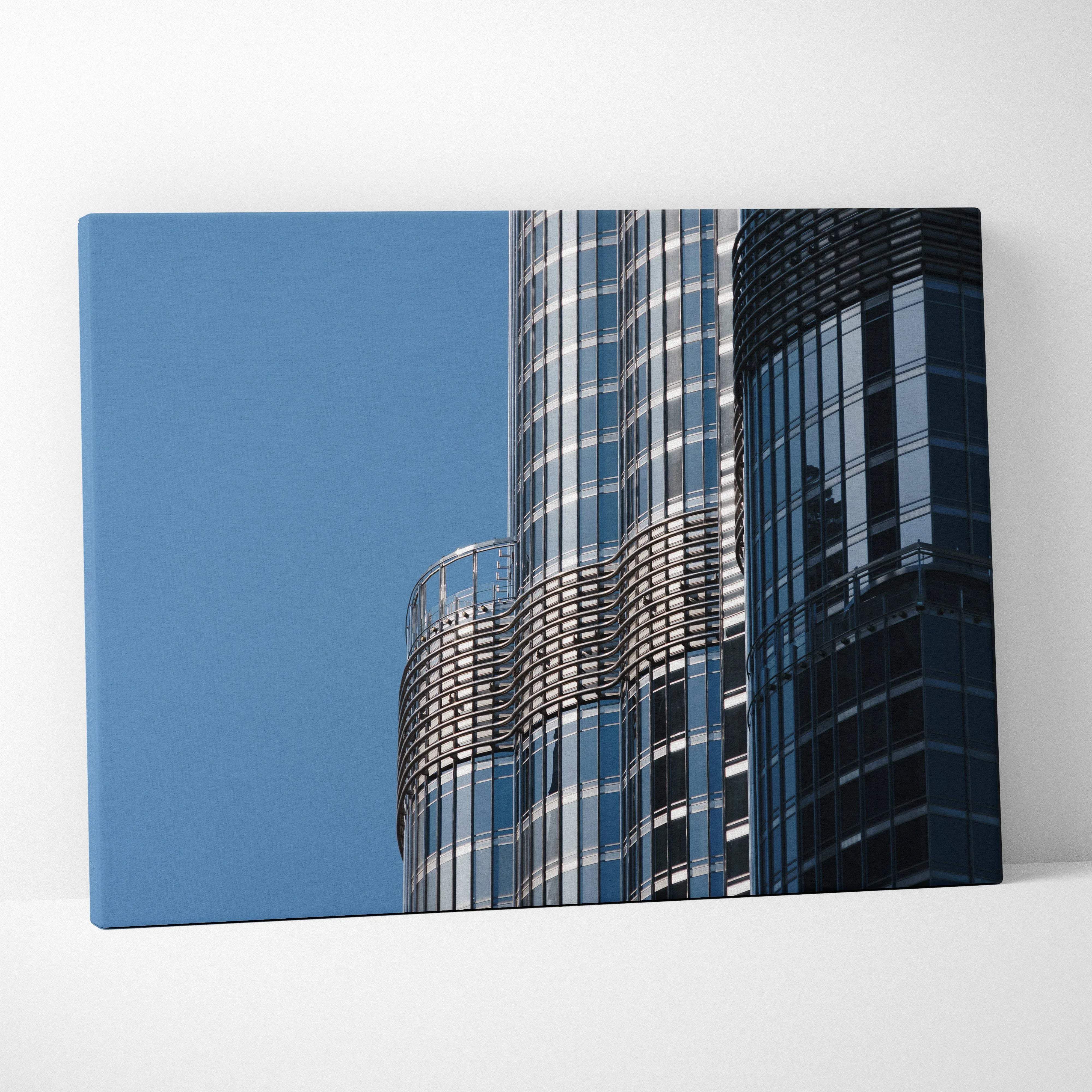 A modern canvas print featuring two sleek glass skyscrapers with cool blue facades for contemporary living
