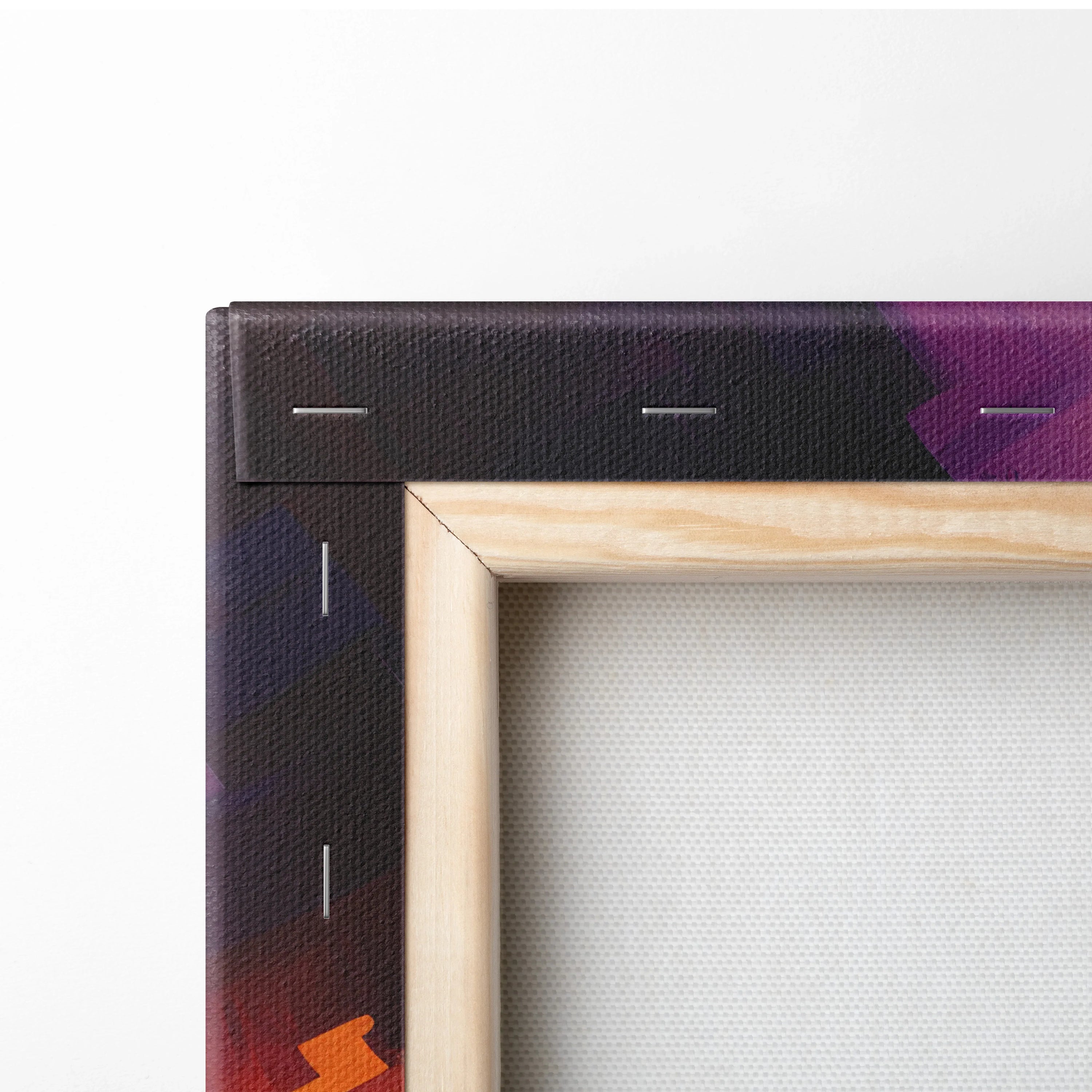 Close-up of wooden canvas frame with staples securing vibrant purple and orange abstract printed fabric edge.