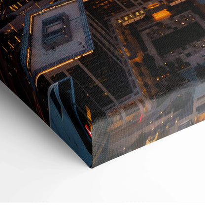 Close-up of stretched canvas wall art featuring illuminated modern architecture at night with warm orange and yellow lights.
