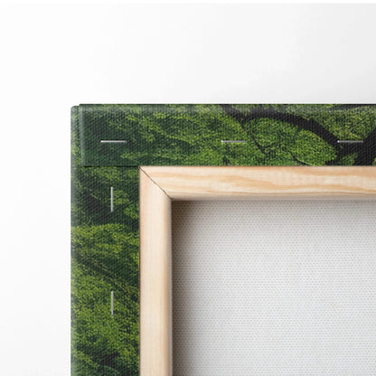 Close-up of wooden framed canvas wall art with green forest scene and stitching details.