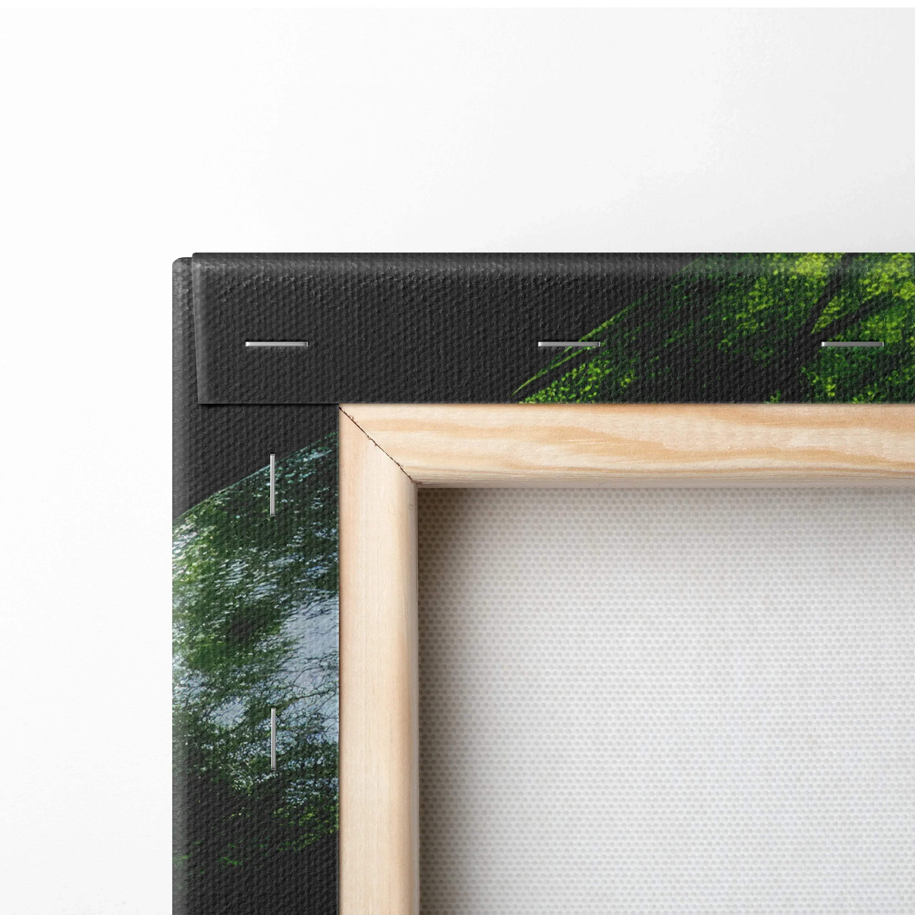 Corner detail of black gallery-wrapped canvas wall art with forest treetops decor and wooden stretcher bars.