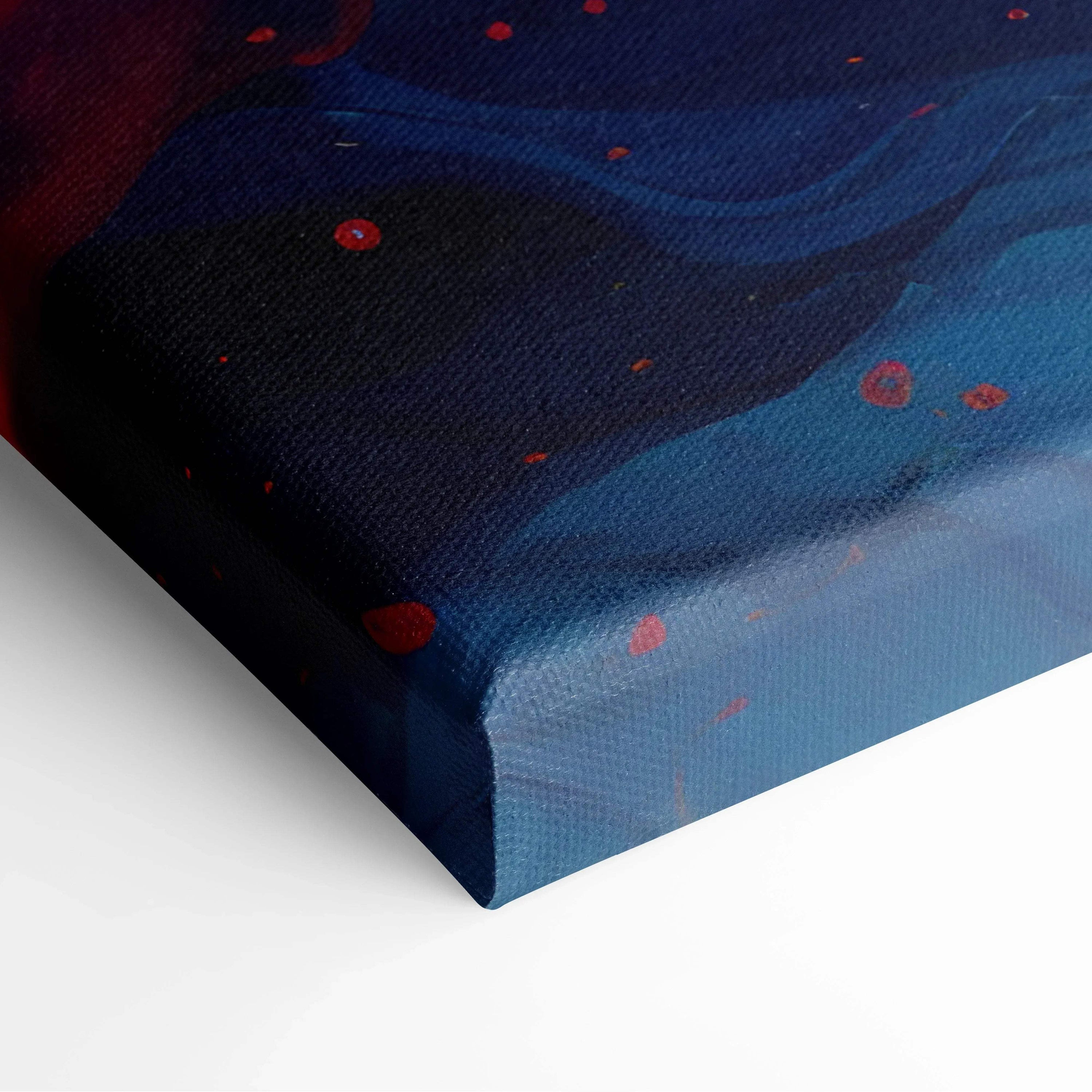 Corner of a vibrant abstract canvas wall art featuring deep blue and red swirls with scattered red dots on textured fabric.