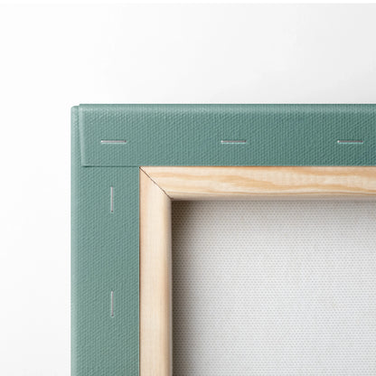 Close-up of canvas wall art showing wooden frame with tropical green fabric edges and stapled corners.