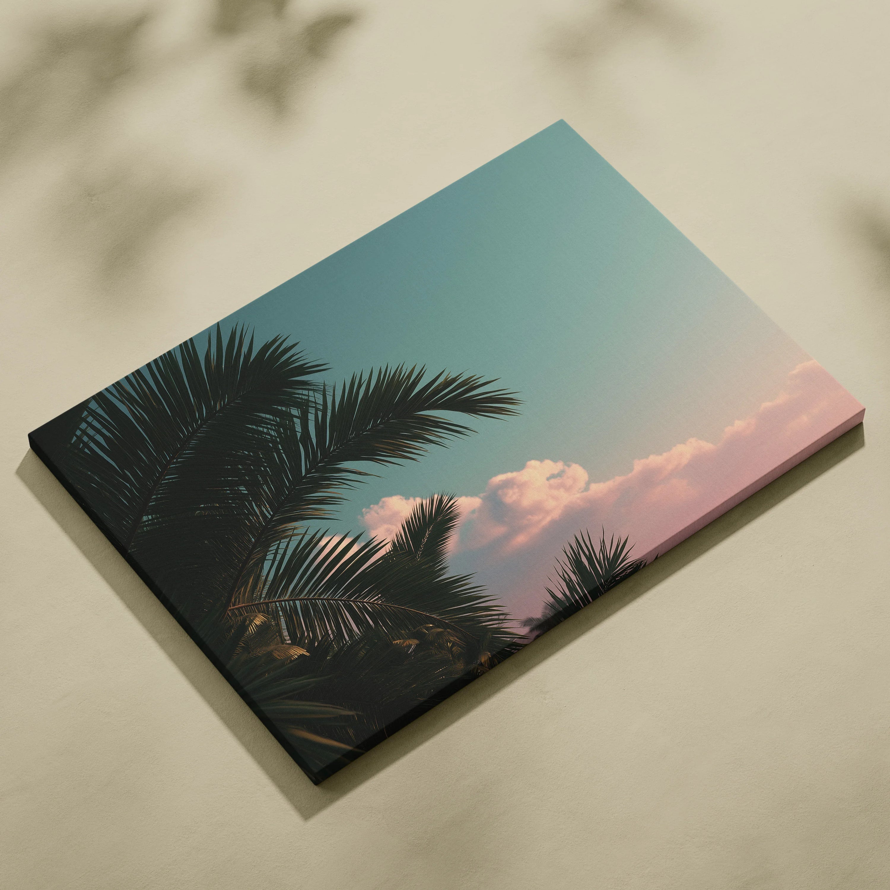 Canvas wall art featuring dark green tropical palm leaves against a pastel blue sky with soft pink clouds.