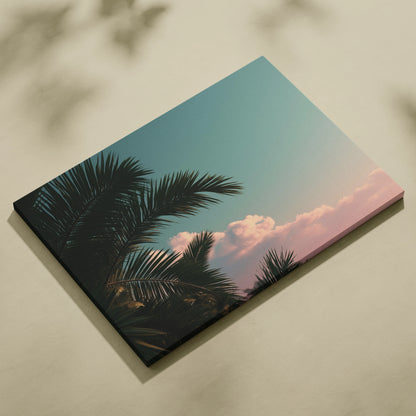 Canvas wall art featuring dark green tropical palm leaves against a pastel blue sky with soft pink clouds.