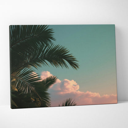 Canvas wall art featuring dark green tropical palm leaves against a soft sunset sky with pink clouds.