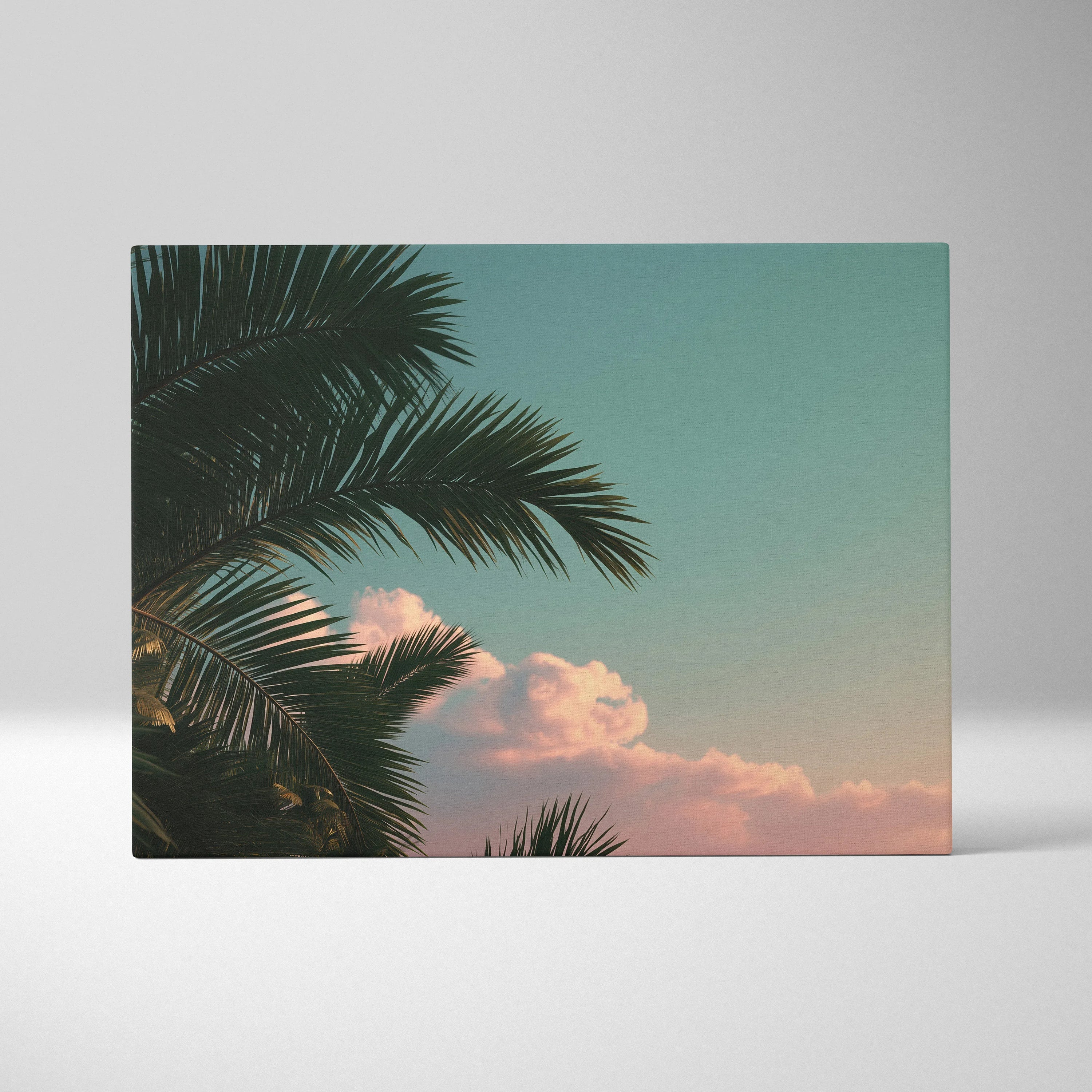Canvas wall art featuring dark green palm leaves against a pastel sky with soft pink clouds, tropical decor.