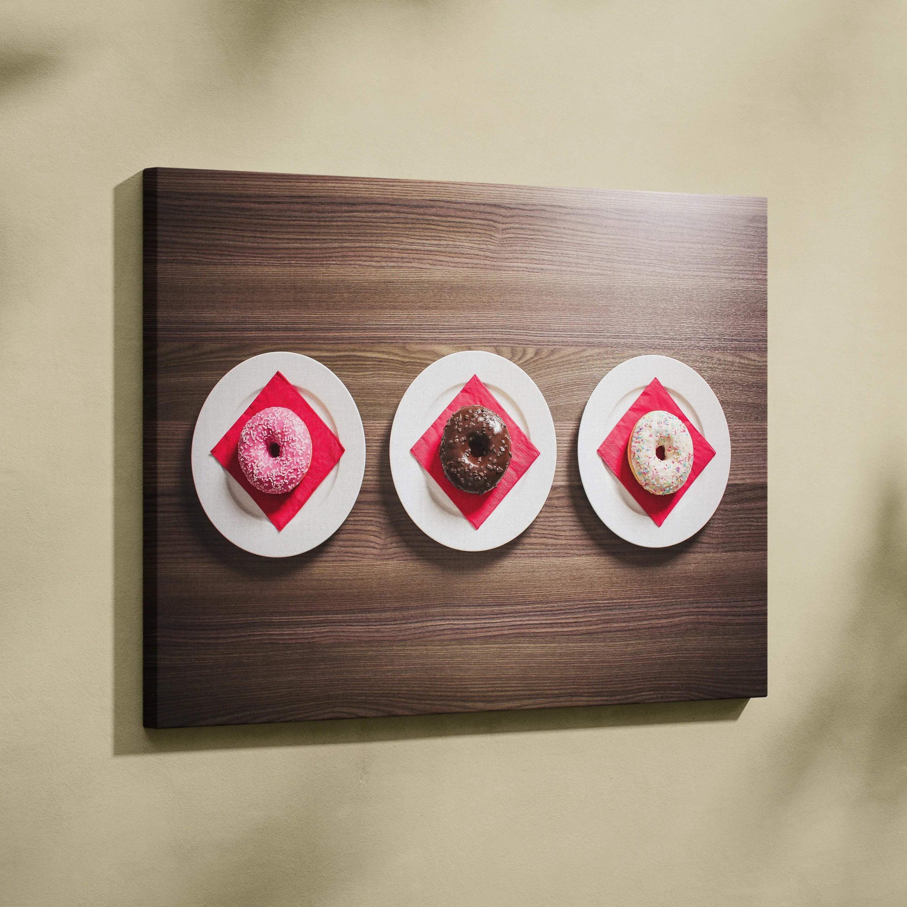 Canvas wall art featuring three glazed donuts on white plates with red napkins, set against a dark wood background.