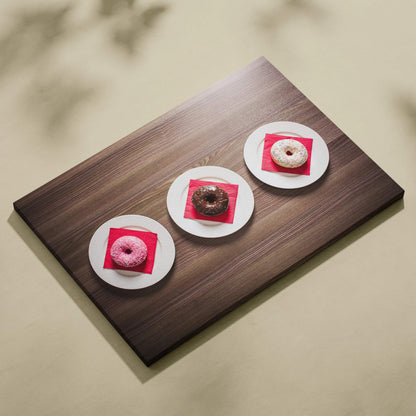 Canvas wall art print featuring three colorful glazed donuts on white plates against a wooden surface background.