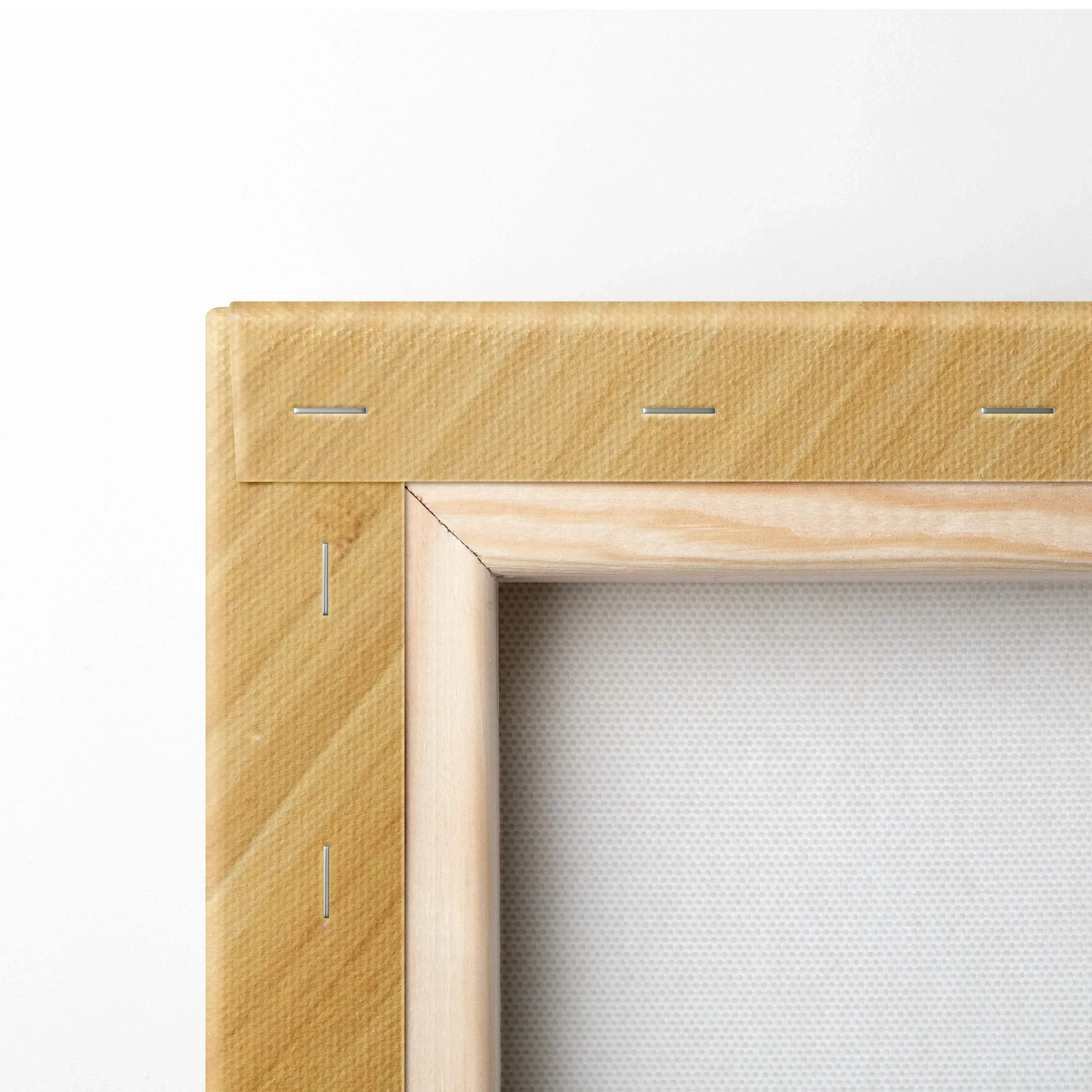 Close-up of wooden stretcher bars with staple-secured edges on the back of a blank white canvas wall art panel.