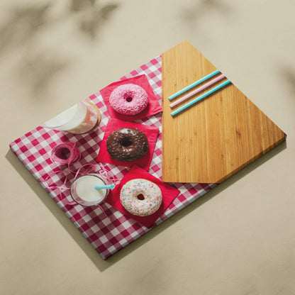 Colorful canvas wall art featuring three sprinkled donuts and milk glasses on a red gingham tablecloth with a wooden cutting