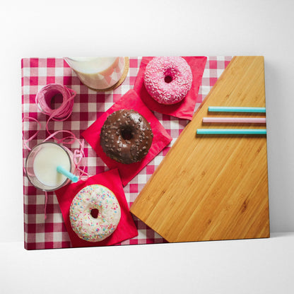 Canvas wall art featuring four colorful donuts with sprinkles on a red-and-white checkered tablecloth, accompanied by a.