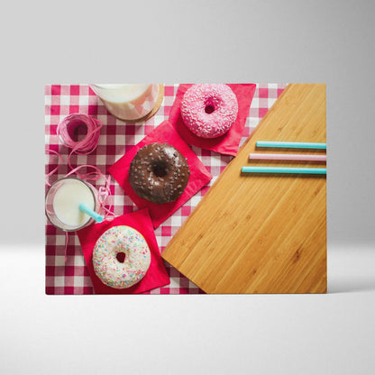 Canvas wall art featuring three colorful donuts with sprinkles on red napkins over a pink and white checkered background,.