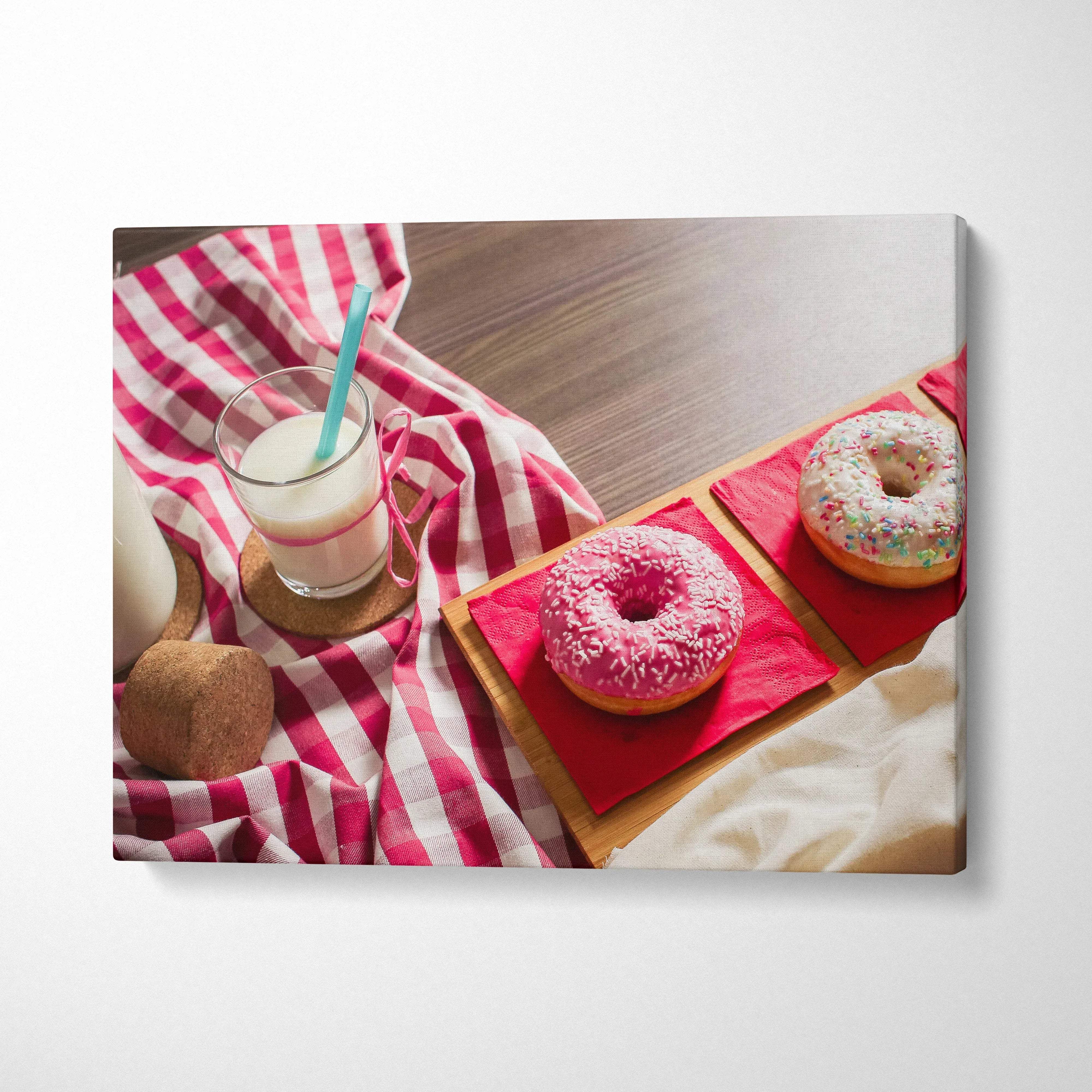 Canvas wall art featuring vibrant pink and white frosted donuts with sprinkles on a wooden table with a red and white.