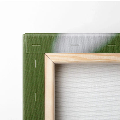 Close-up of wooden frame and green canvas edge with visible staples on white fabric backing.