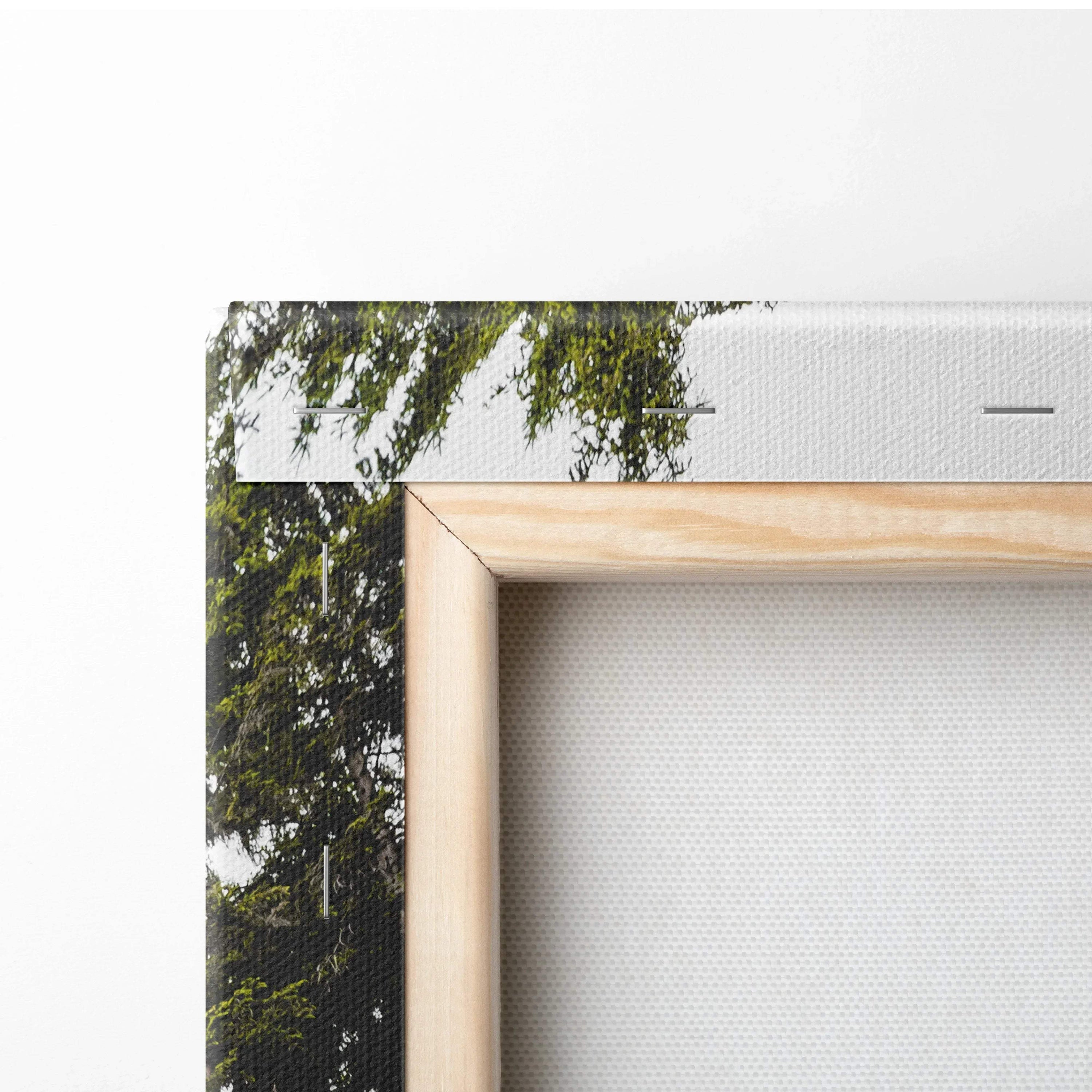 Close-up of canvas wall art showing natural wood frame and forest scene with green foliage and sunset light.