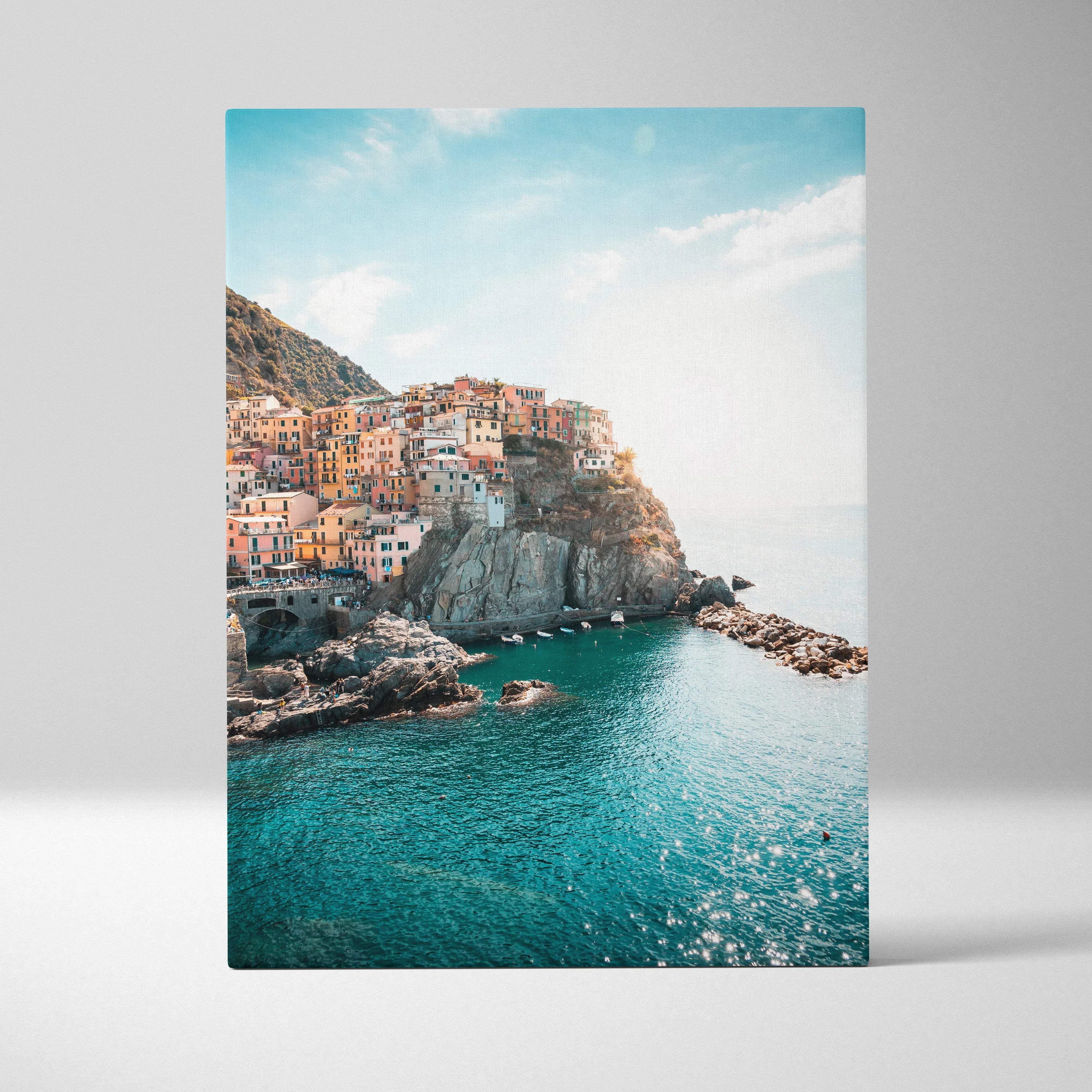 A vibrant canvas wall art of a sunlit coastal italian village with pastel buildings and turquoise waters
