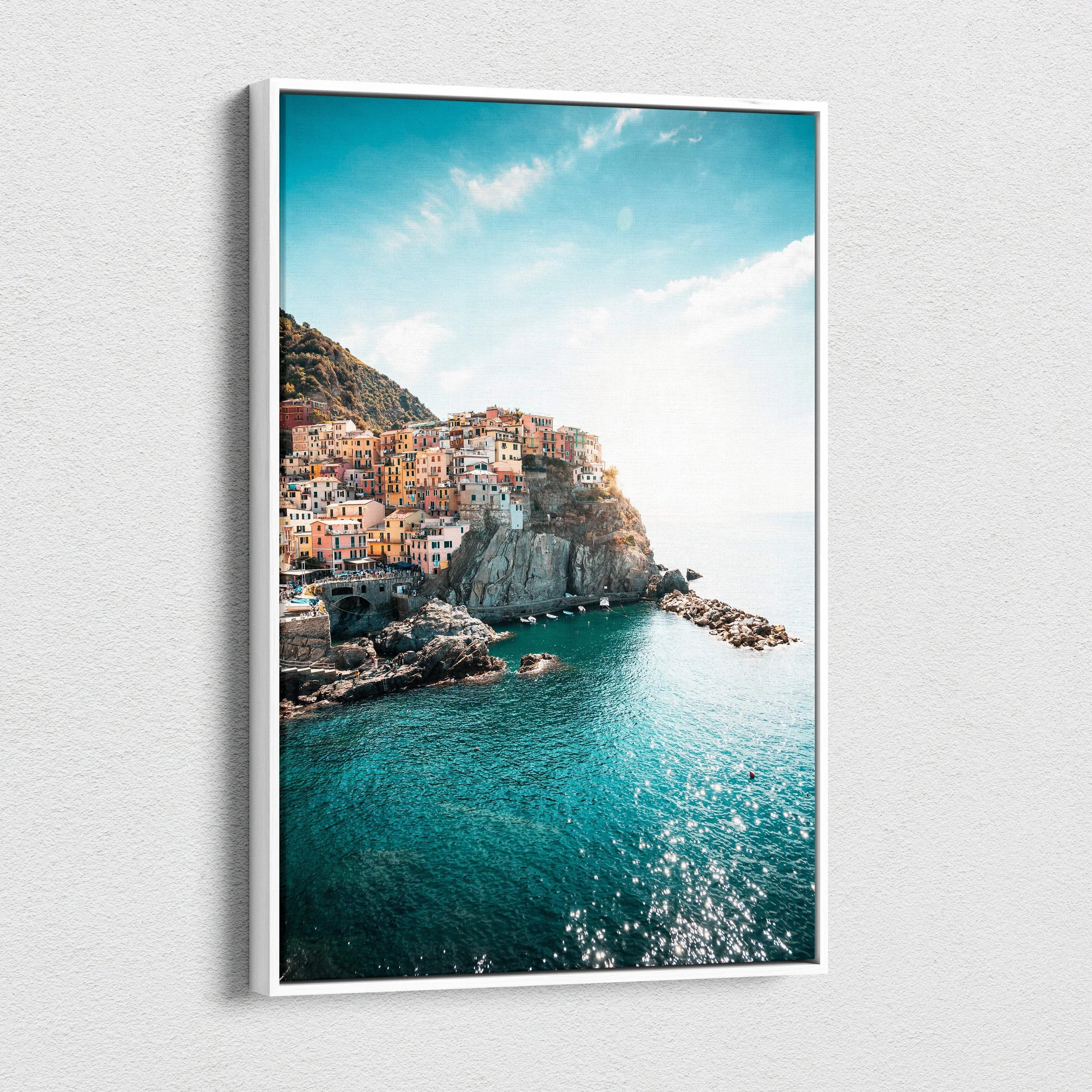 Canvas wall art featuring colorful Italian coastal buildings on rocky cliffs with vibrant turquoise sea under a bright blue.