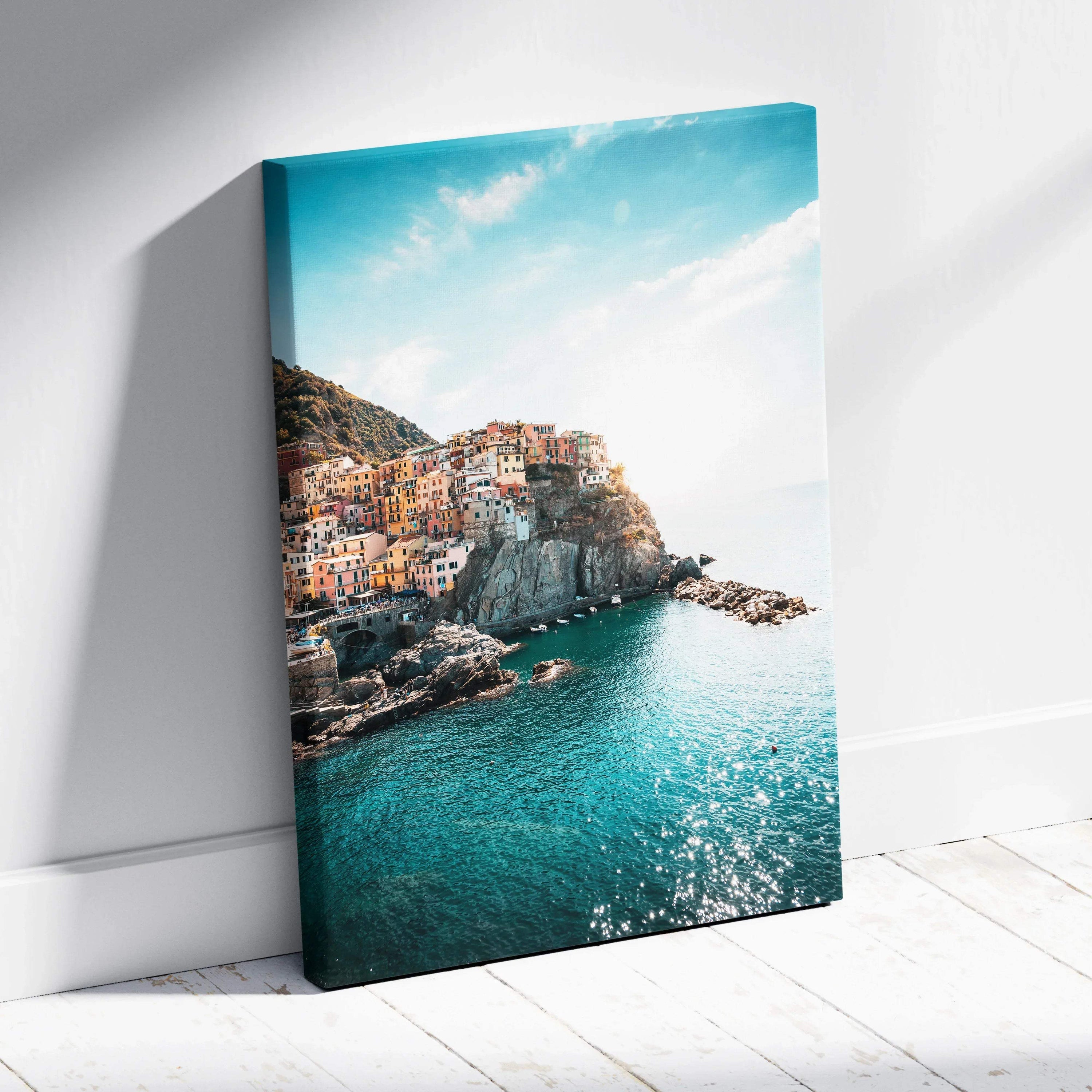 Canvas wall art featuring colorful buildings on cliffs above bright blue sea under a partly cloudy sky.