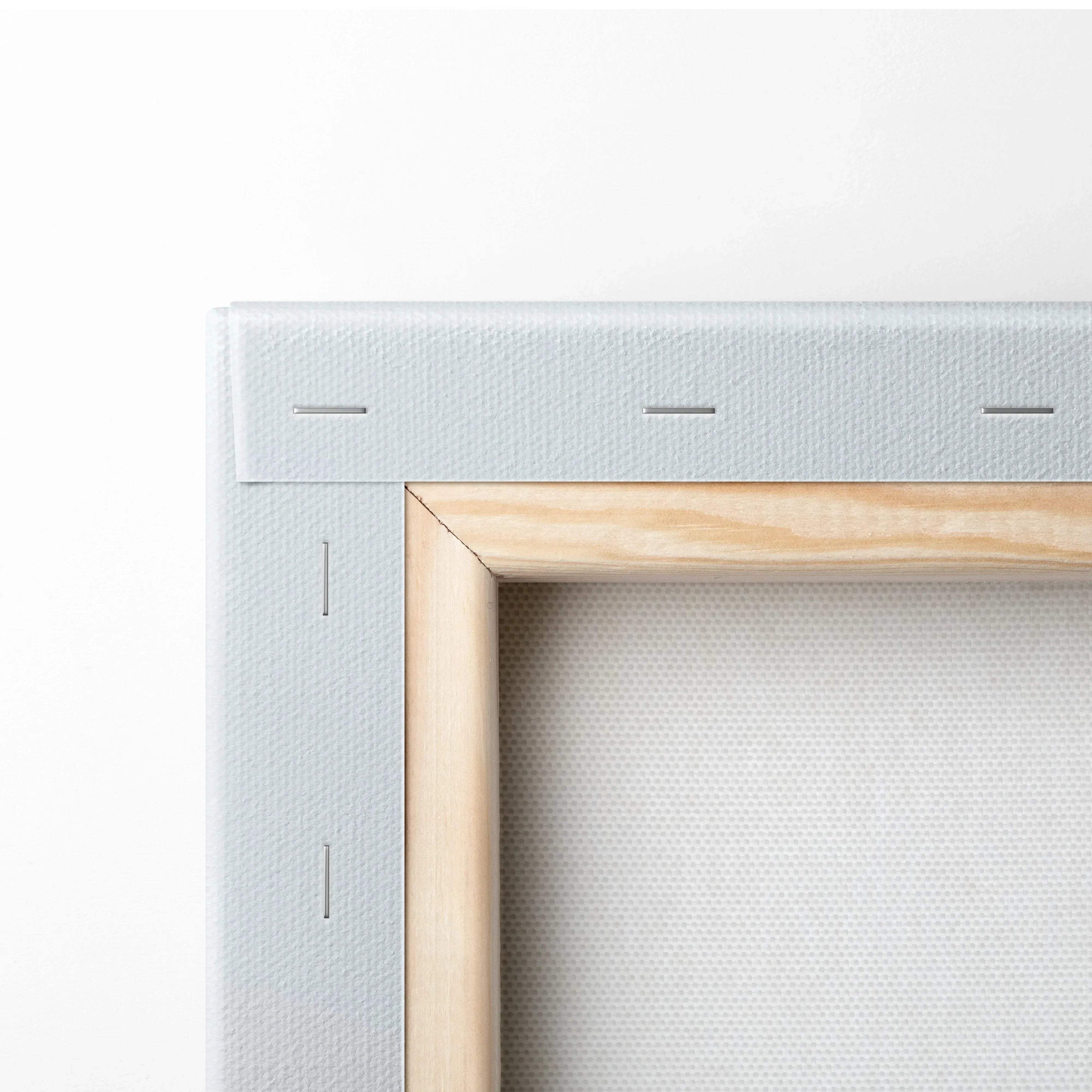 Close-up of stretched white canvas fabric on wooden frame with visible staples, showcasing wall art construction.