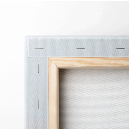 Close-up of stretched white canvas fabric on wooden frame with visible staples, showcasing wall art construction.