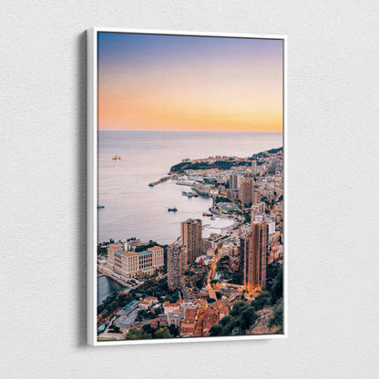 Vertical canvas wall art featuring a vibrant sunset over Monaco's coastal cityscape with high-rise buildings and a calm sea.