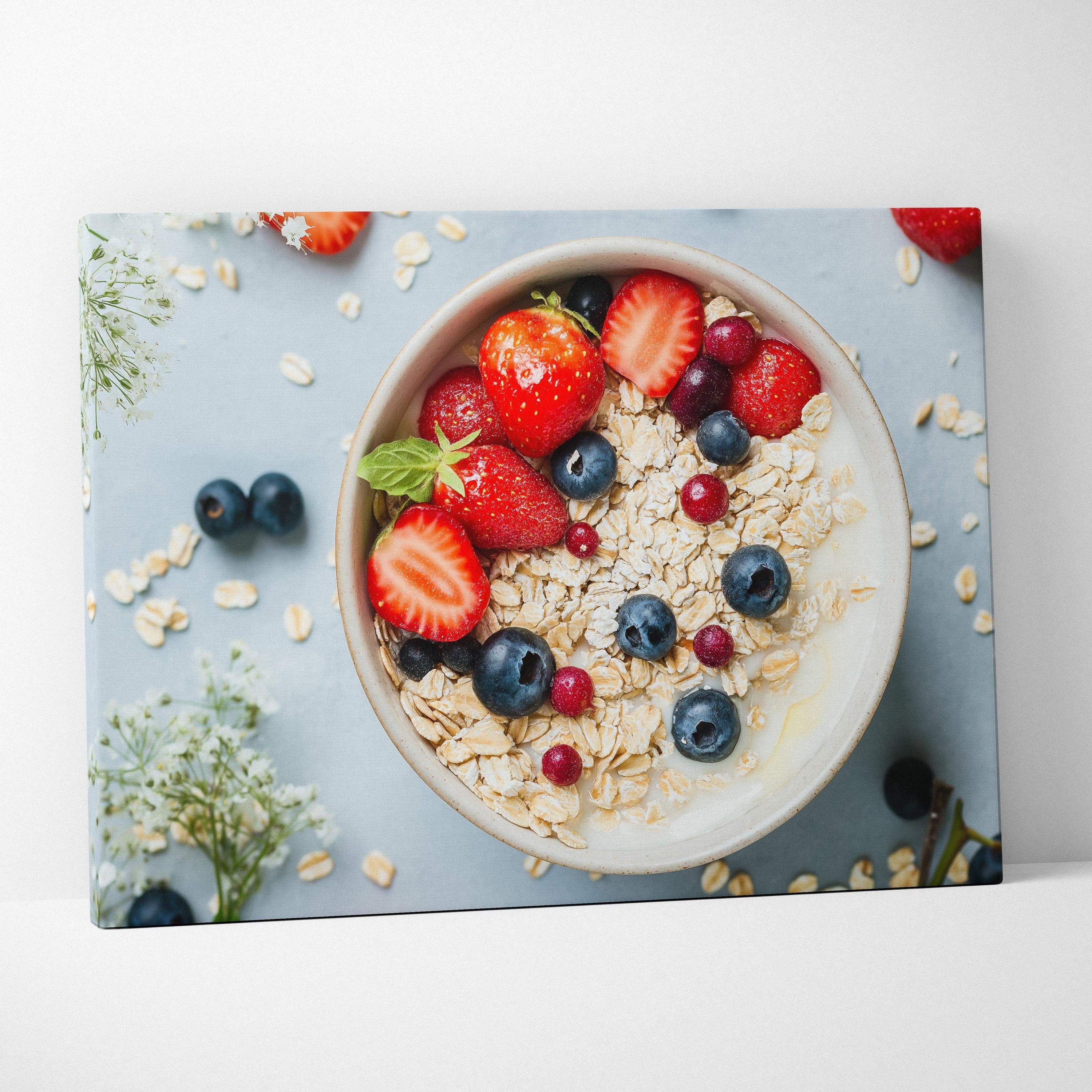 Canvas wall art featuring a breakfast bowl with granola, strawberries, blueberries, and raspberries on a pale blue.