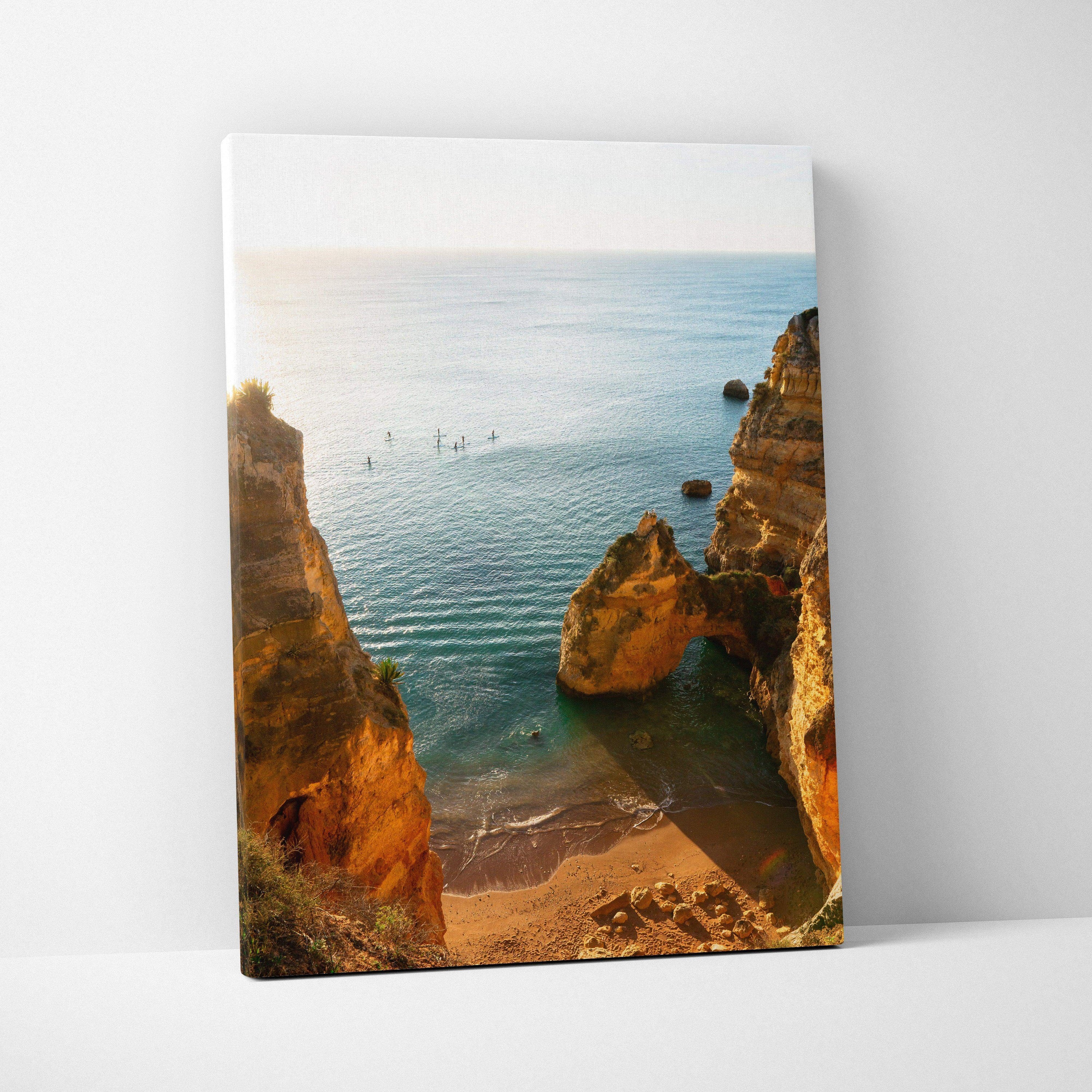 Canvas wall art featuring a serene beach scene with golden rock formations and calm blue ocean waters.
