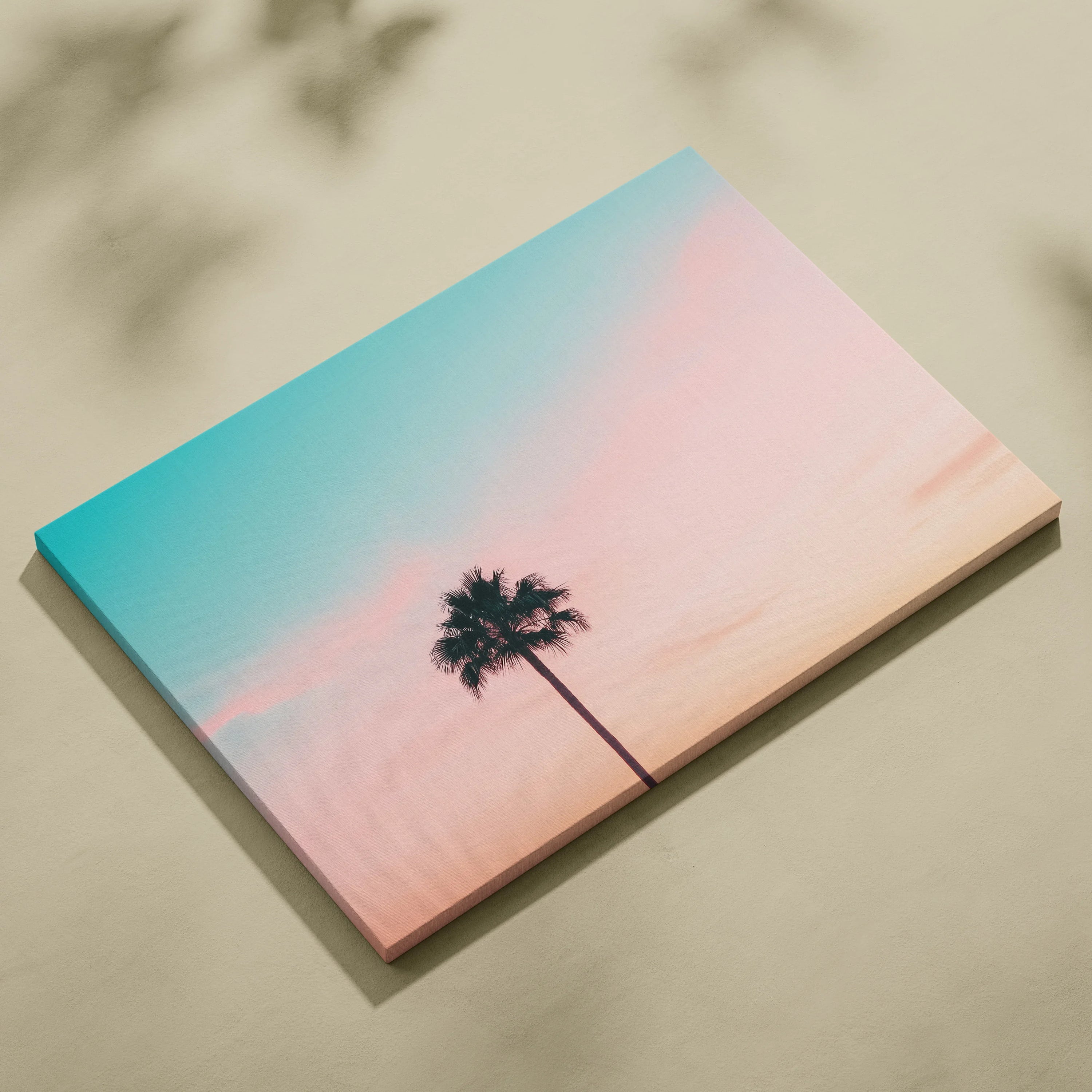 Minimalist canvas wall art featuring a black palm tree silhouette against a pastel sunset sky in soft pink and blue tones.
